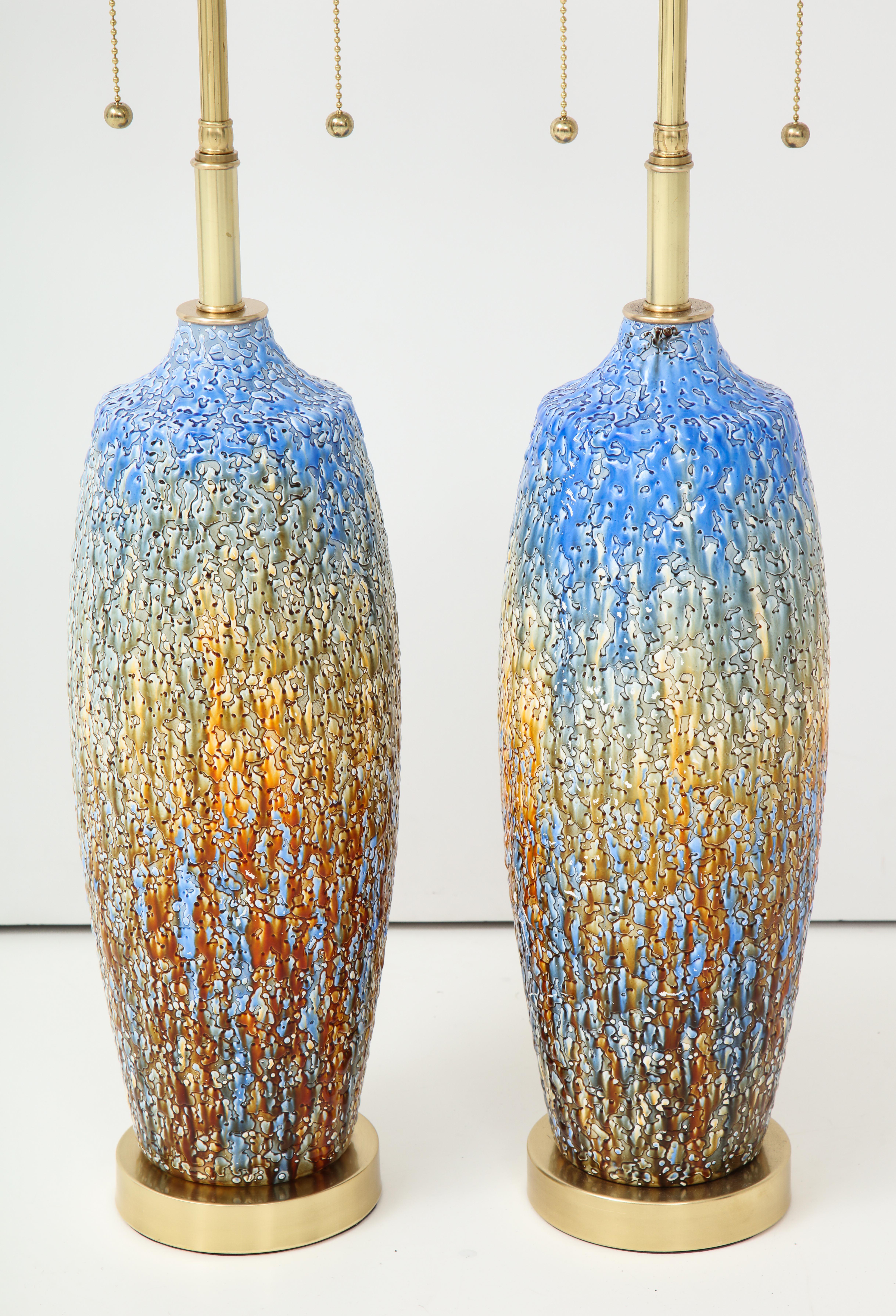 Pair of 1960s Italian ceramic lamps with a textured glaze finish.
The lamps are mounted on polished brass bases and they have
been newly rewired with polished brass double clusters.
        