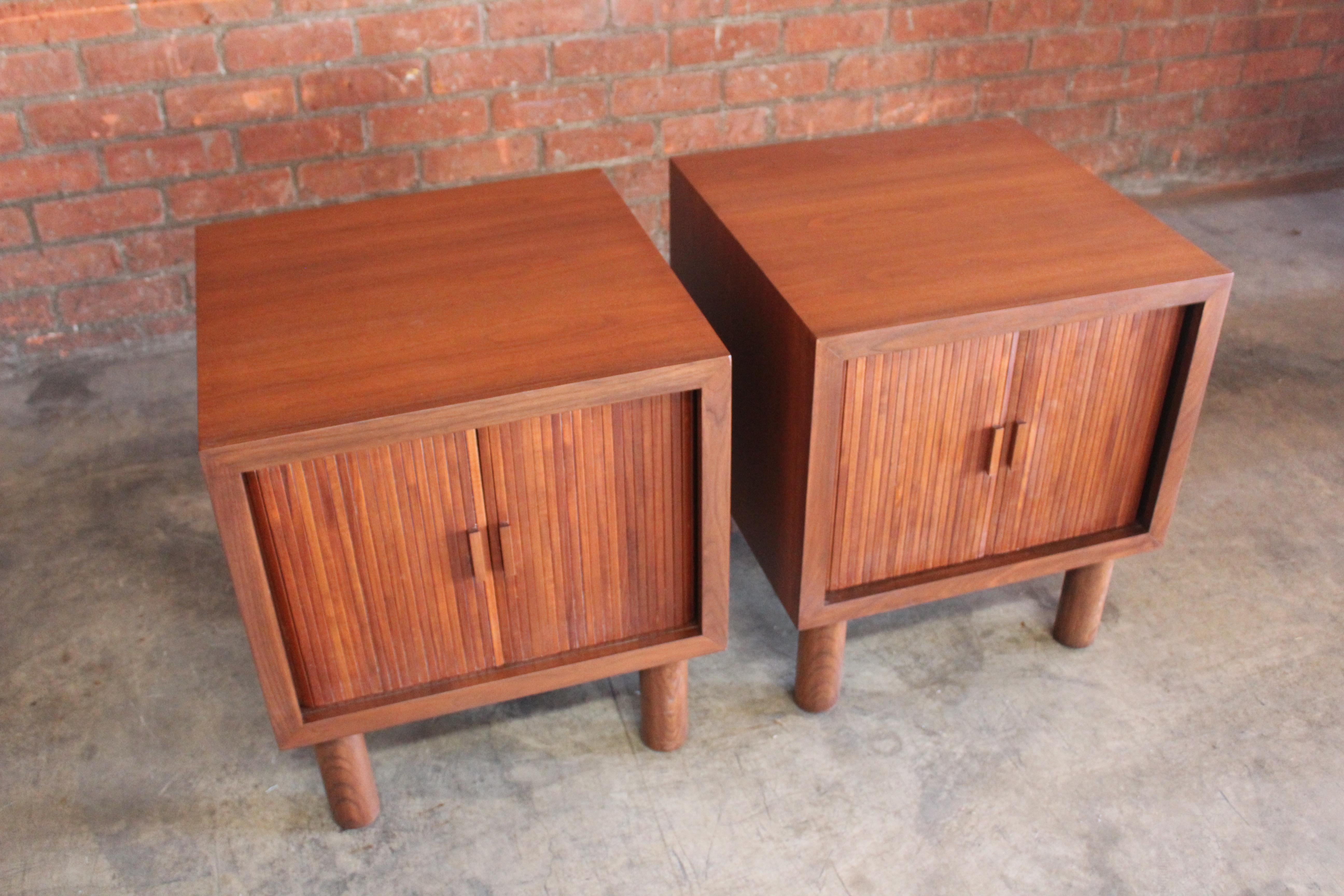Pair of 1960s walnut nightstands with tambour doors. They have been refinished. 
The backs of the nightstands have some veneer repairs.