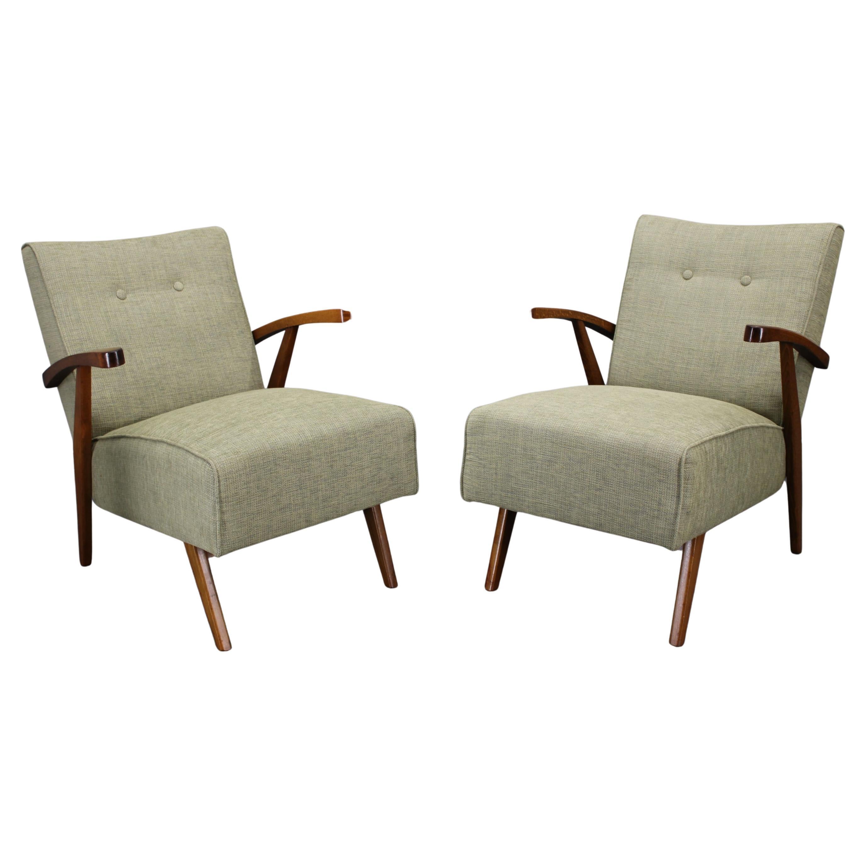 Dieses raffinierte Paar tschechoslowakischer Sessel aus den 1960er Jahren ist ein Beispiel für die Eleganz und Handwerkskunst des mitteleuropäischen Designs der Jahrhundertmitte. Die Stühle mit massiven Buchenbeinen und geschwungenen Armlehnen