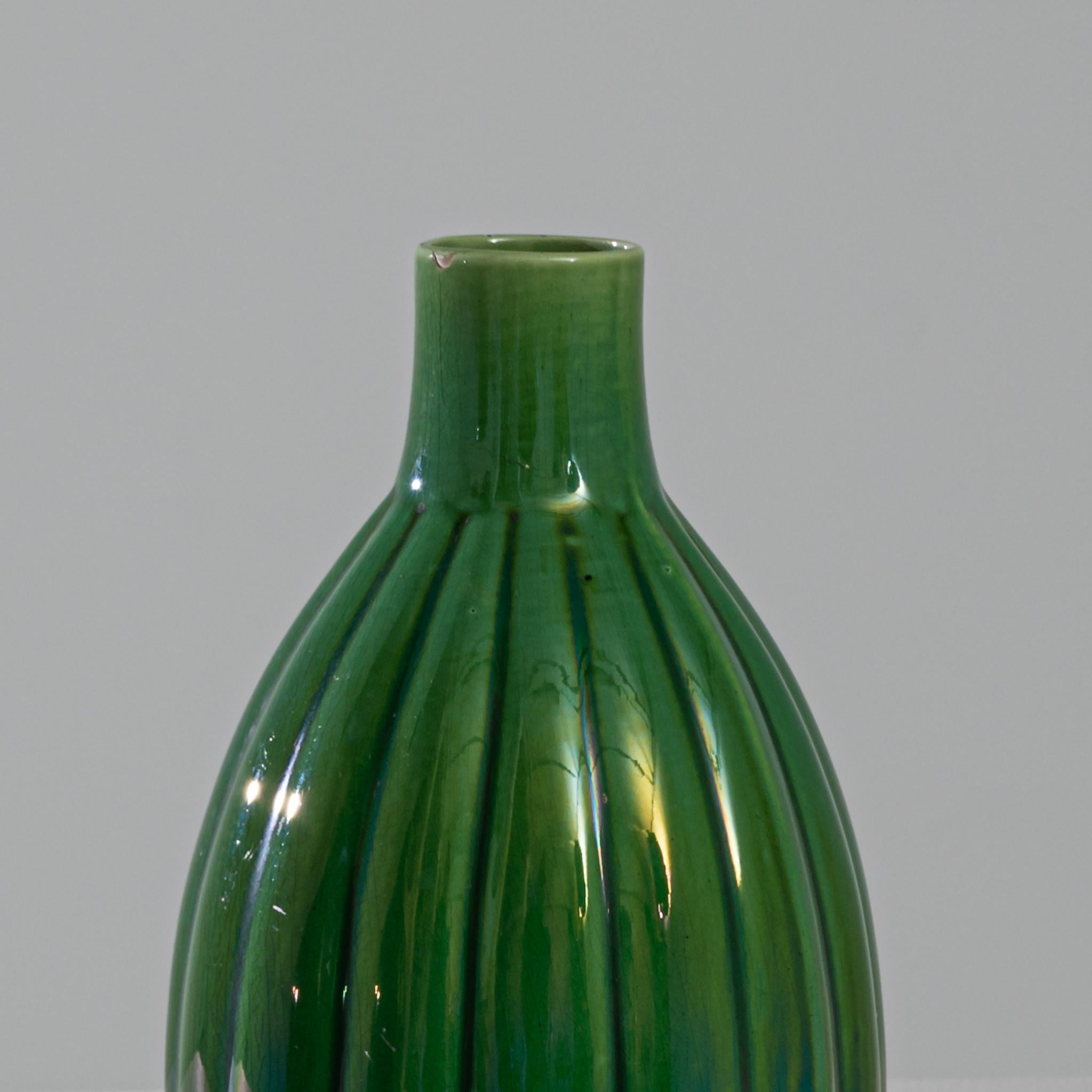 Immerse yourself in the enchanting allure of this pair of 1960s Belgian ceramic vases. Standing proudly in a rich forest green hue, these vessels are adorned with elegant vertical lines that gracefully traverse their surfaces. What sets them aglow