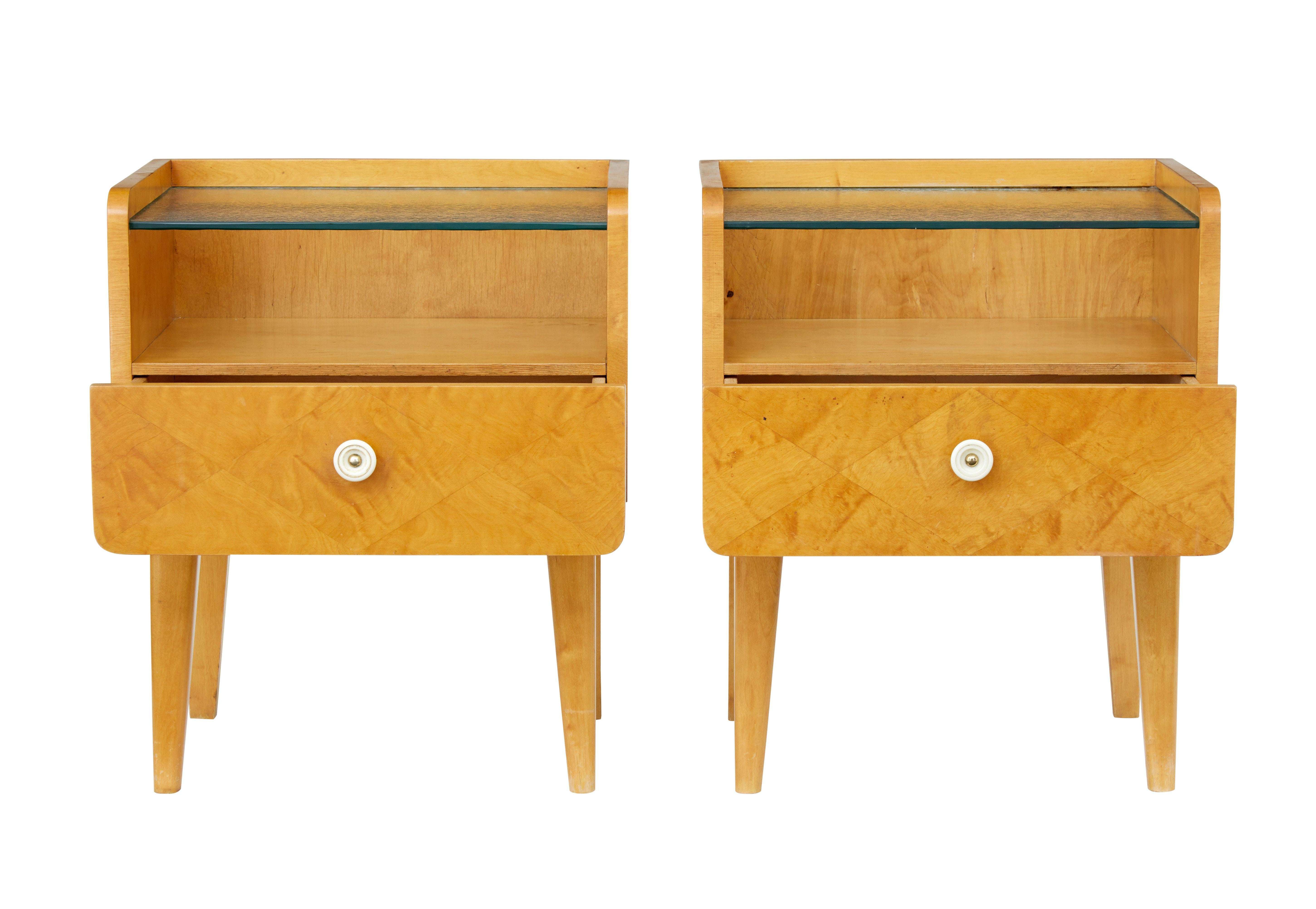 Pair of Scandinavian birch bedside tables, circa 1960.

Inset frosted glass top surface with a single patterned veneered drawer to the front. Standing on tapered legs.

Minor marks to wood work.