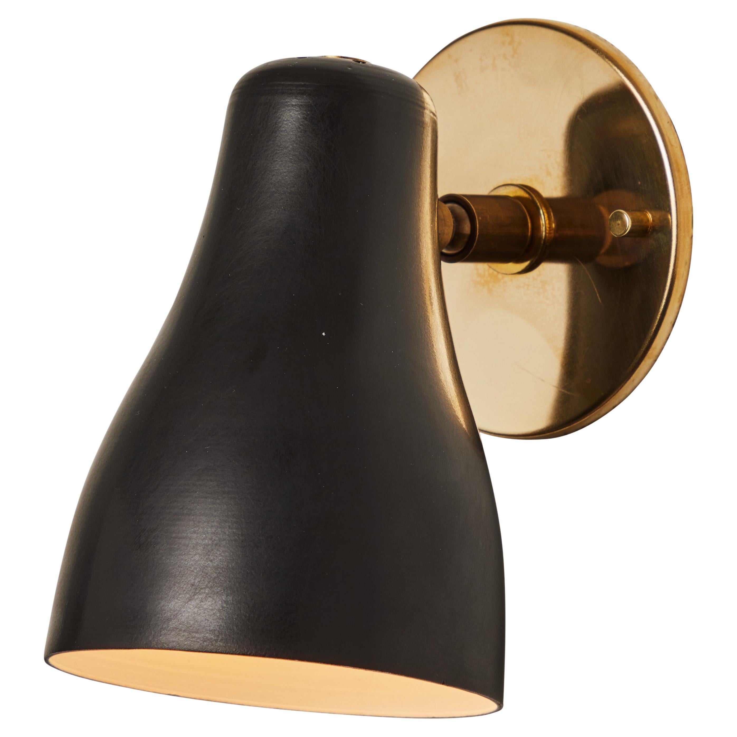 Pair of 1960s black and brass wall lamps attributed to Jacques Biny. 

An exceptionally clean and simple design executed in brass with a black metal shade. Lamp rotates freely on adjustable swivel. Quintessentially midcentury French in its