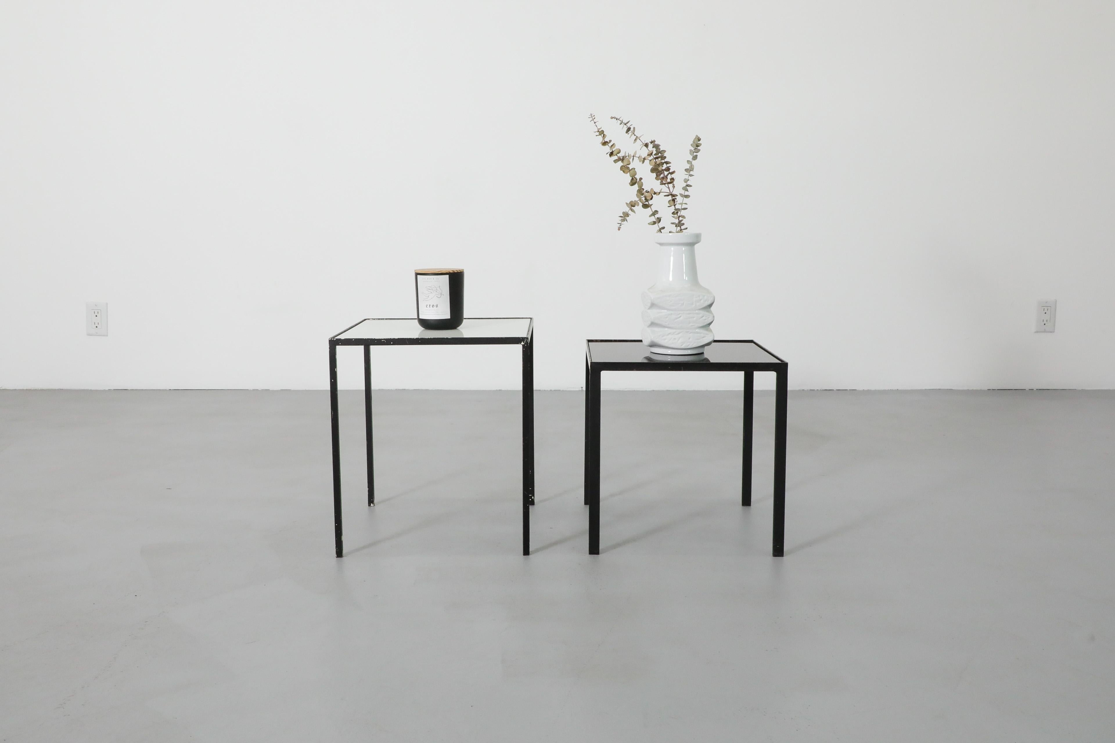 Pair of Mid-Century side tables by Dutch furniture manufacterer Artimeta. Features black enameled metal frames with white & black square glass tops making this a set of two stylish, contrasting side tables that  can be placed apart or together to