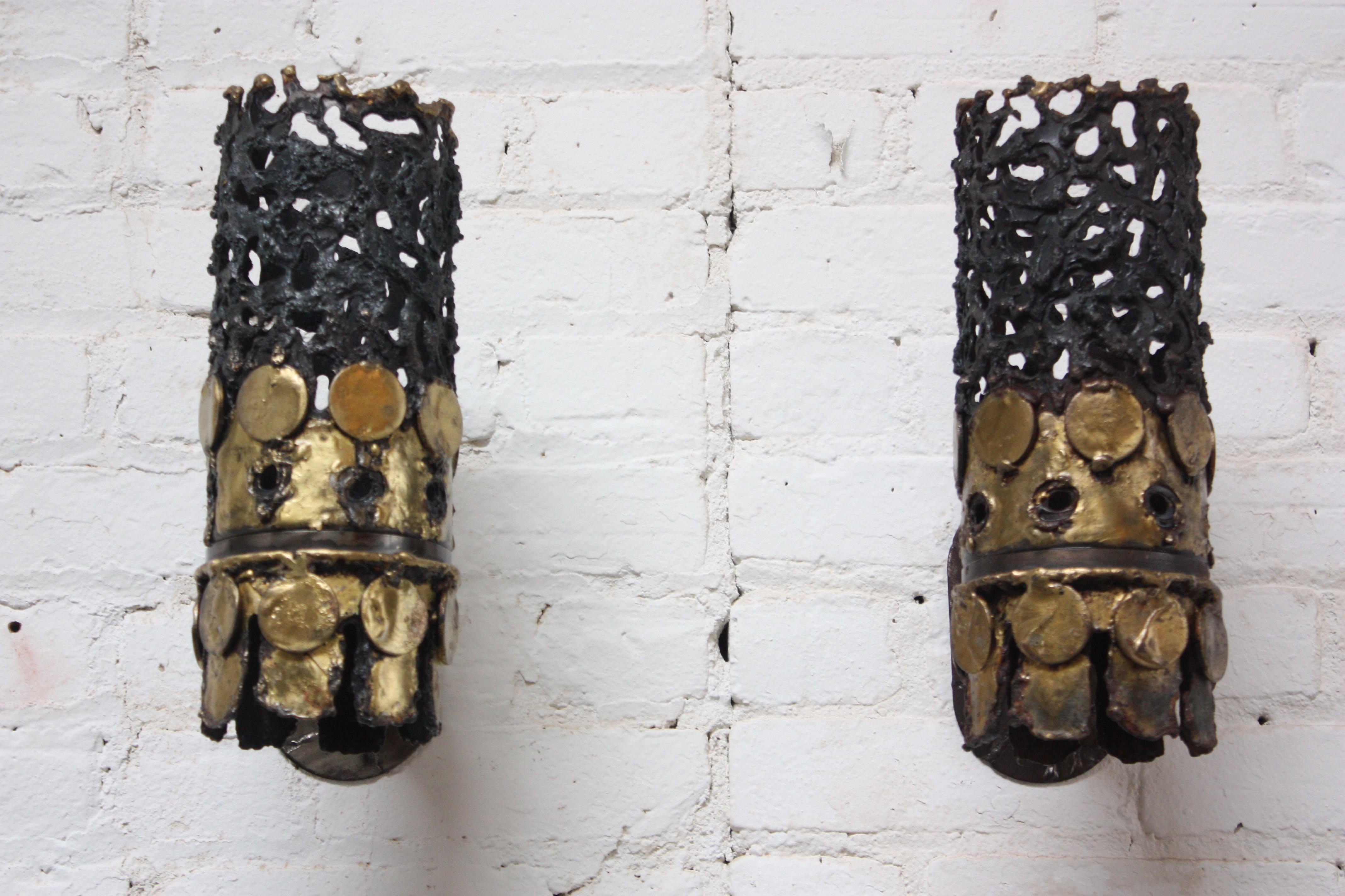 Mid-Century Modern (likely Scandinavian) cylindrical torch-cut steel and brass wall sconces in the Brutalist style. Designed with soldered, interlocking steel fittings which connect the sconces to a steel plate for wall-mounting to accommodate the