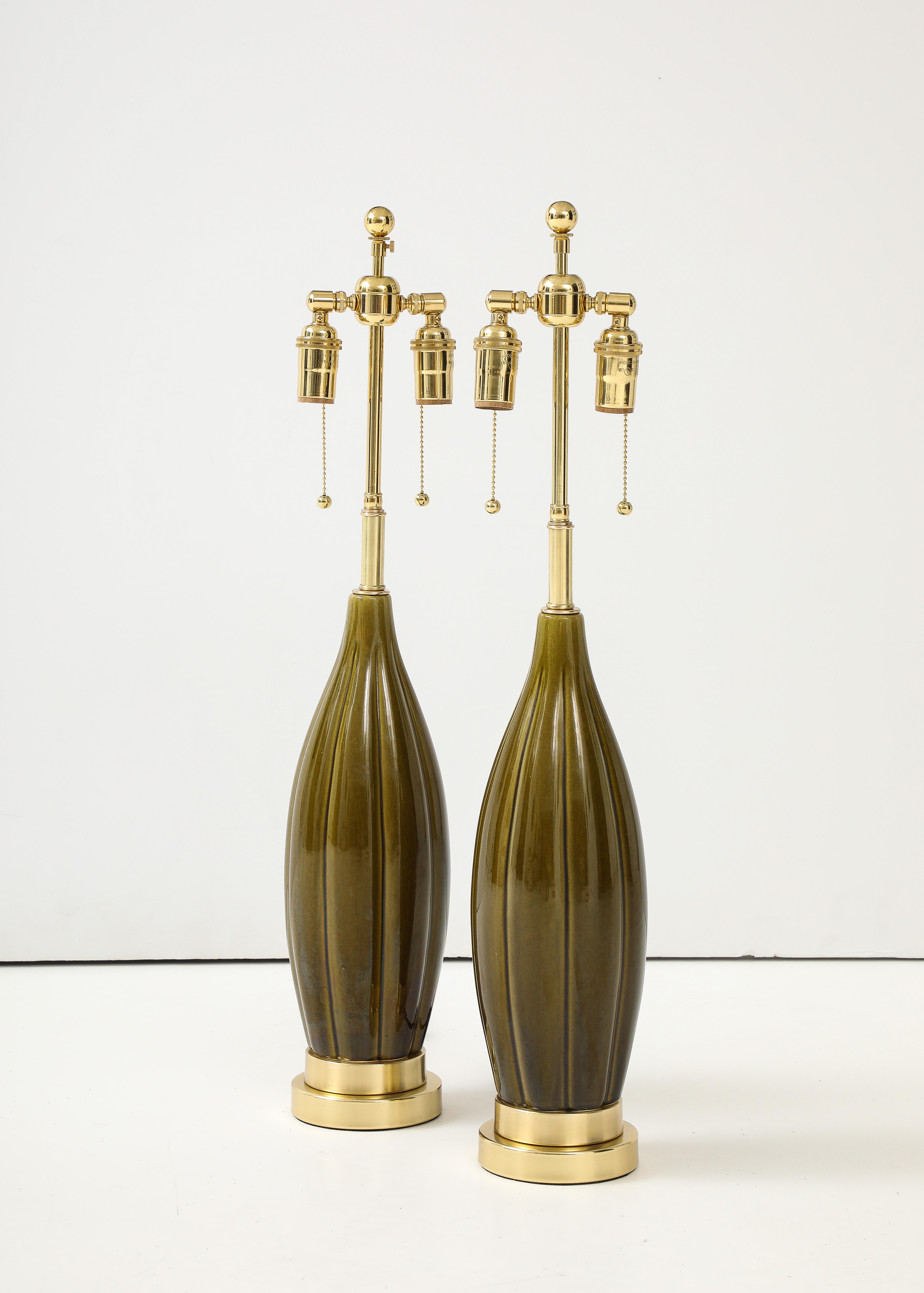 Pair of 1960's ceramic lamps with a moss green glaze
The ceramic lamp bodies are set on tiered brass bases and they have been Newly
rewired with adjustable polished brass double clusters and silk rayon cords.
The lamps take standard size light bulbs