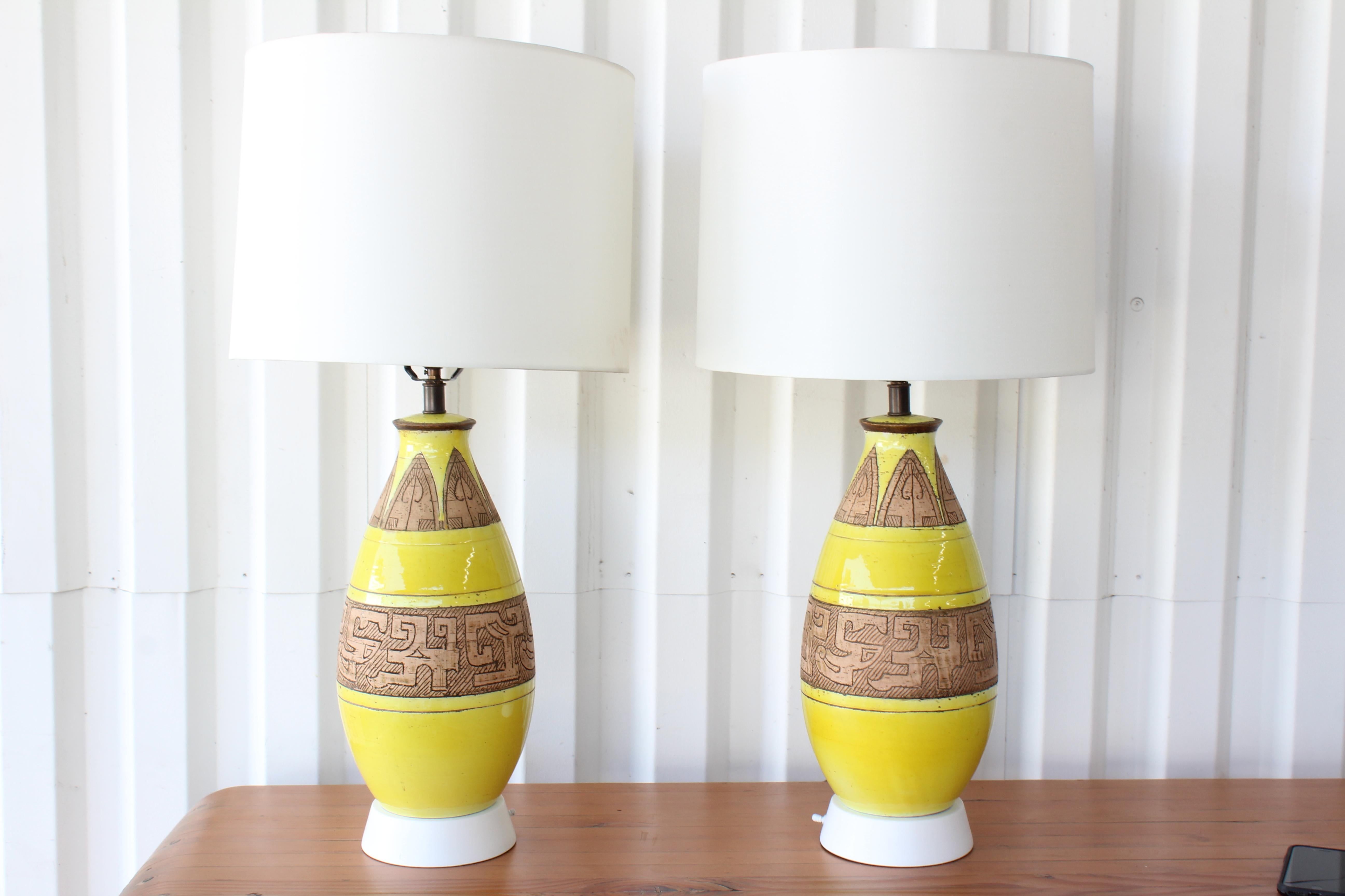Pair of 1960s ceramic porcelain table lamps with a yellow glaze and Egyptian motifs. Newly rewired with silk shades. Newly painted bases in white lacquer. Sold as a pair. 
Measures: 32.5