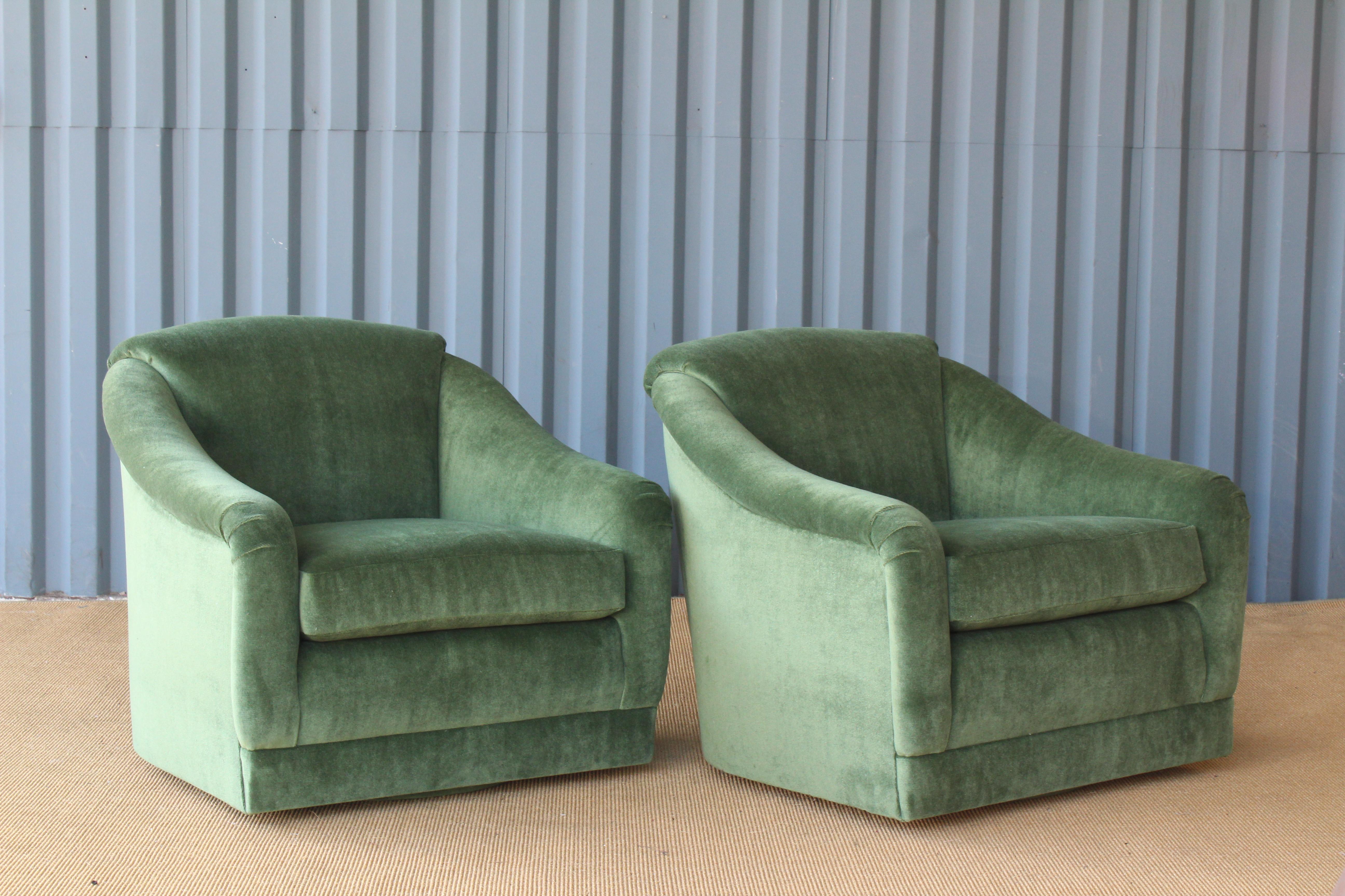 Pair of 1960s club chairs on a swiveling base. The pair have been reupholstered in green wool blend velvet.
