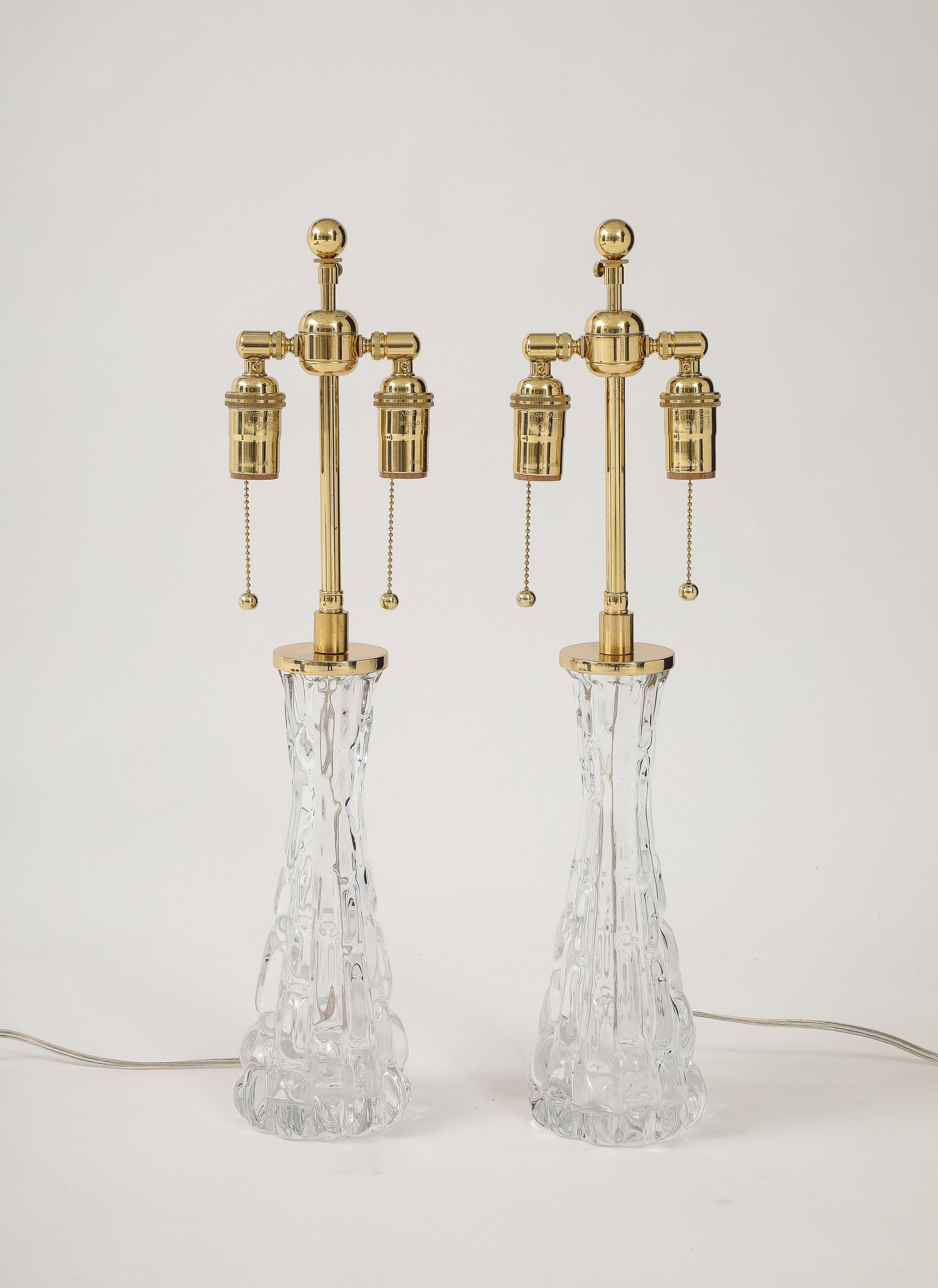 Pair of 1960's Crystal lamps designed  by Carl Fagerlund for Orrefors.
The elegant Crystal lamp bodies resemble frozen water and they have been Newly rewired
with adjustable polish brass double clusters and clear cords.
Each socket takes standard