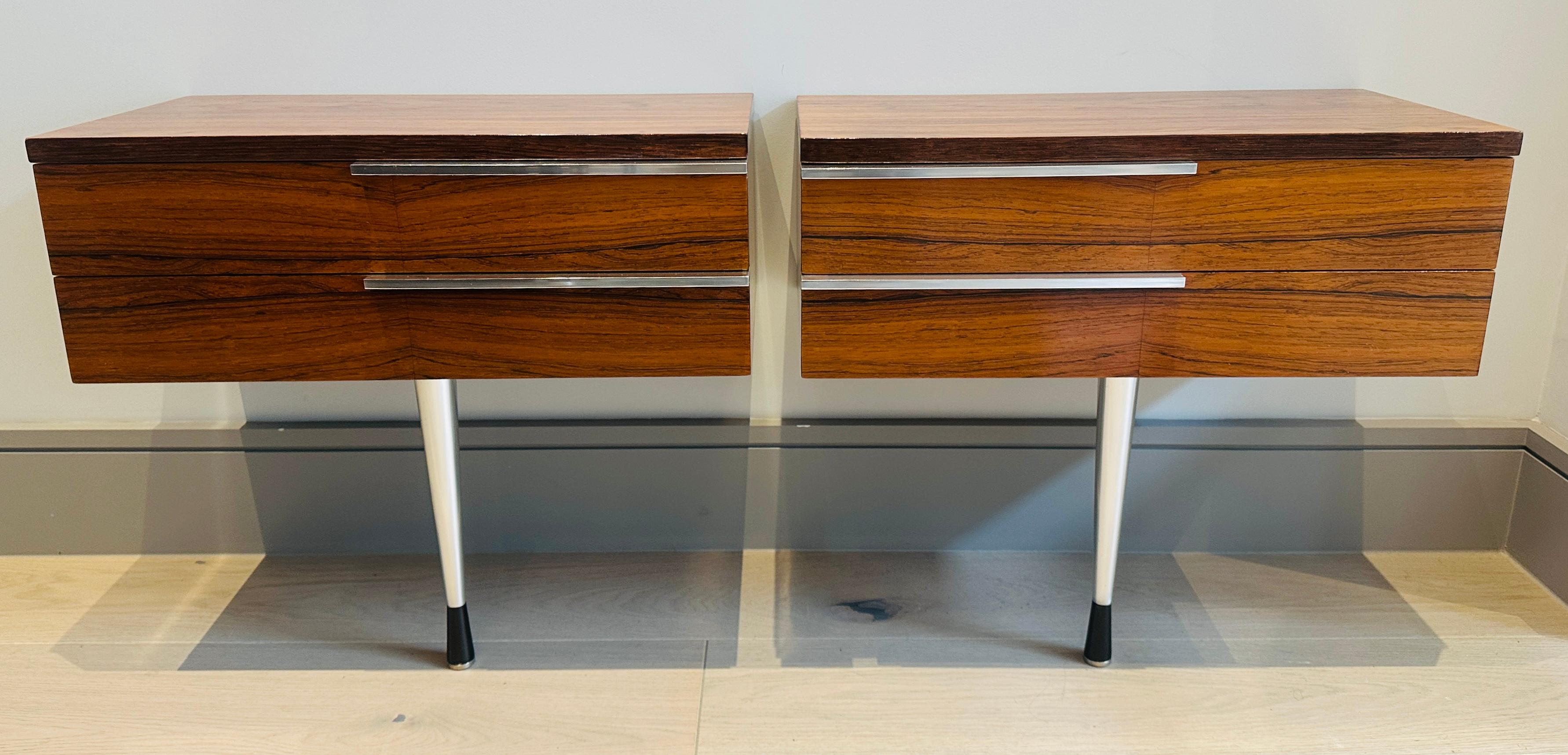 Pair of mid-century modern 1960s Danish rosewood veneer two-drawer bedside tables or nightstands with slim polished chrome pull handles.  The wall hung floating bedside tables are supported by a single chrome slim tapered leg in the front and