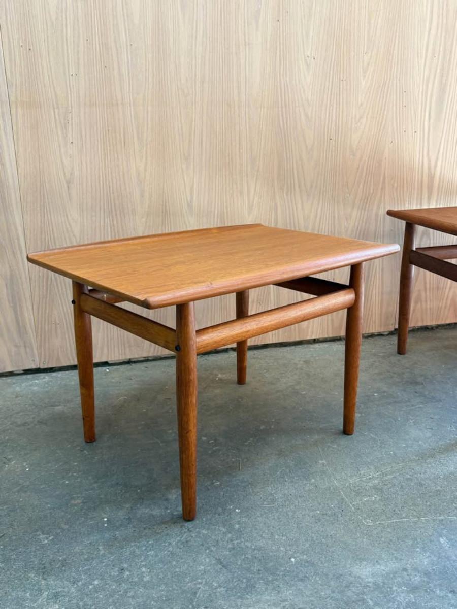 Diseñadas por Grete Jalk para Glostrup Møbelfabrik, este refinado par de mesas auxiliares danesas de teca capta la esencia del modernismo escandinavo de los años 60. Los tableros sutilmente esculpidos y las patas redondeadas están bellamente