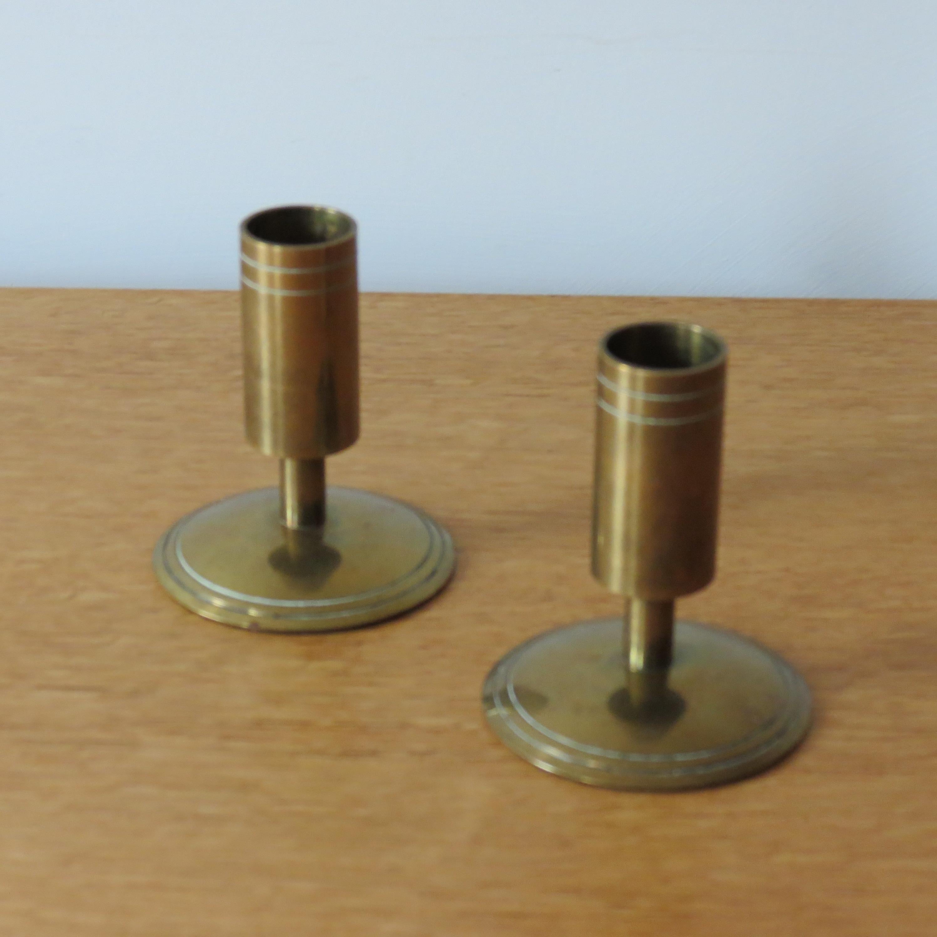 Pair of 1960s candle holders by Danpresent, Denmark. Made from solid brass. In good vintage condition, the brass has tarnished through time. Both candle holders retain the original label to the underside that reads DanPresent Ltd Made in