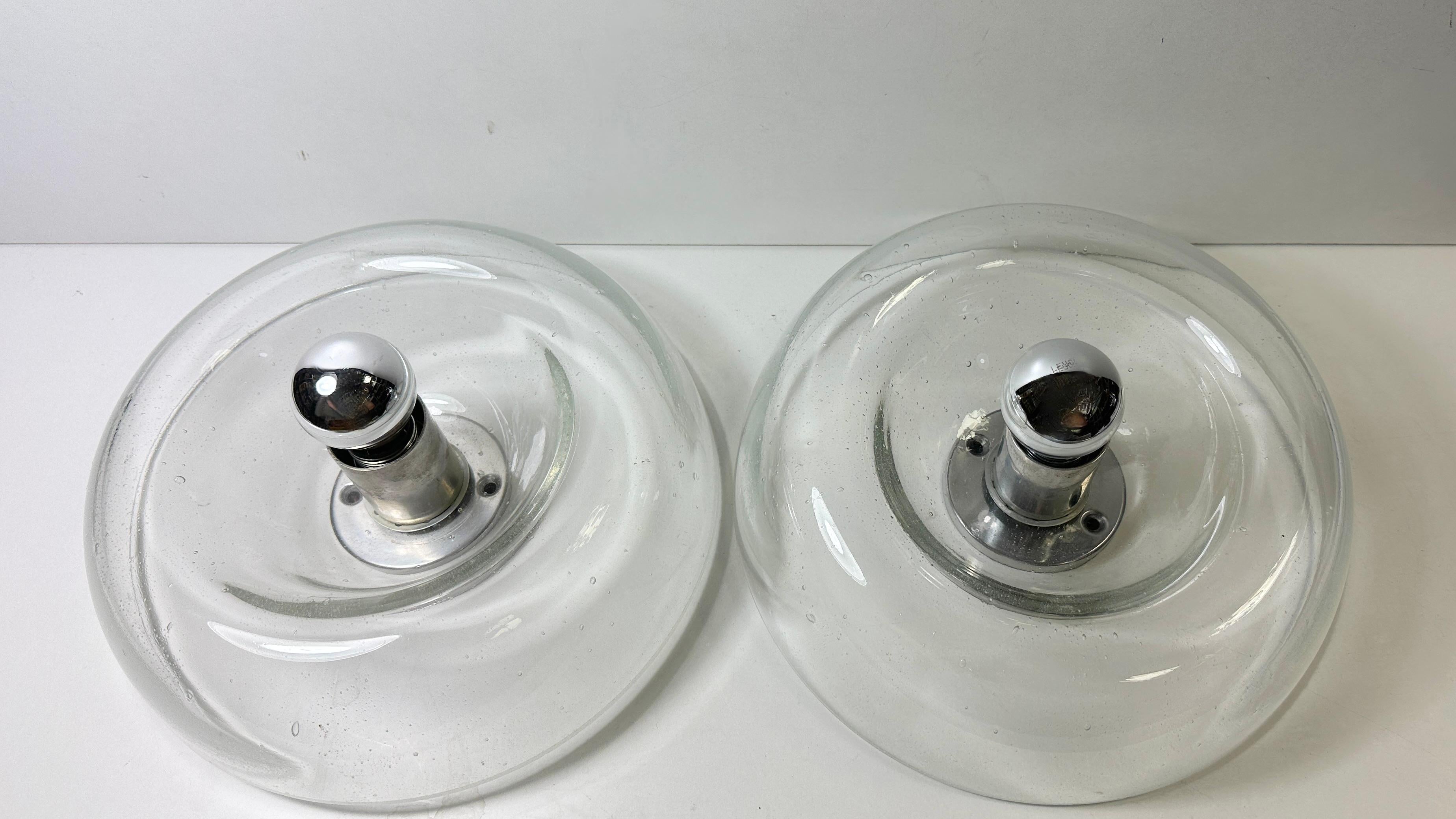 A stunning pair of donut shape glass wall sconces with small air bubble in the glass. Each consisting of a stylish Mid-Century Modern style design. Each fixture requires an European E14 / 110 Volt candelabra bulb, up to 40 watts. Found at an estate