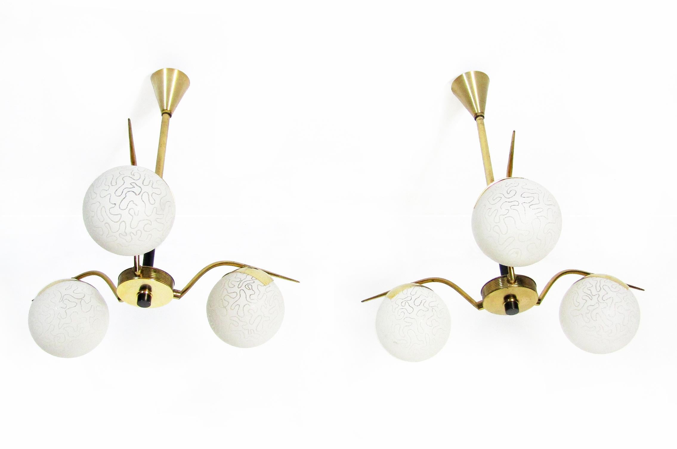 A pair of chic 1960s three-arm globe chandeliers by French makers Maison Arlus.

The shades are made from opaque matt glass with an organic etched design. They are held on angular brass arms with stylish brass holders.

In perfect working