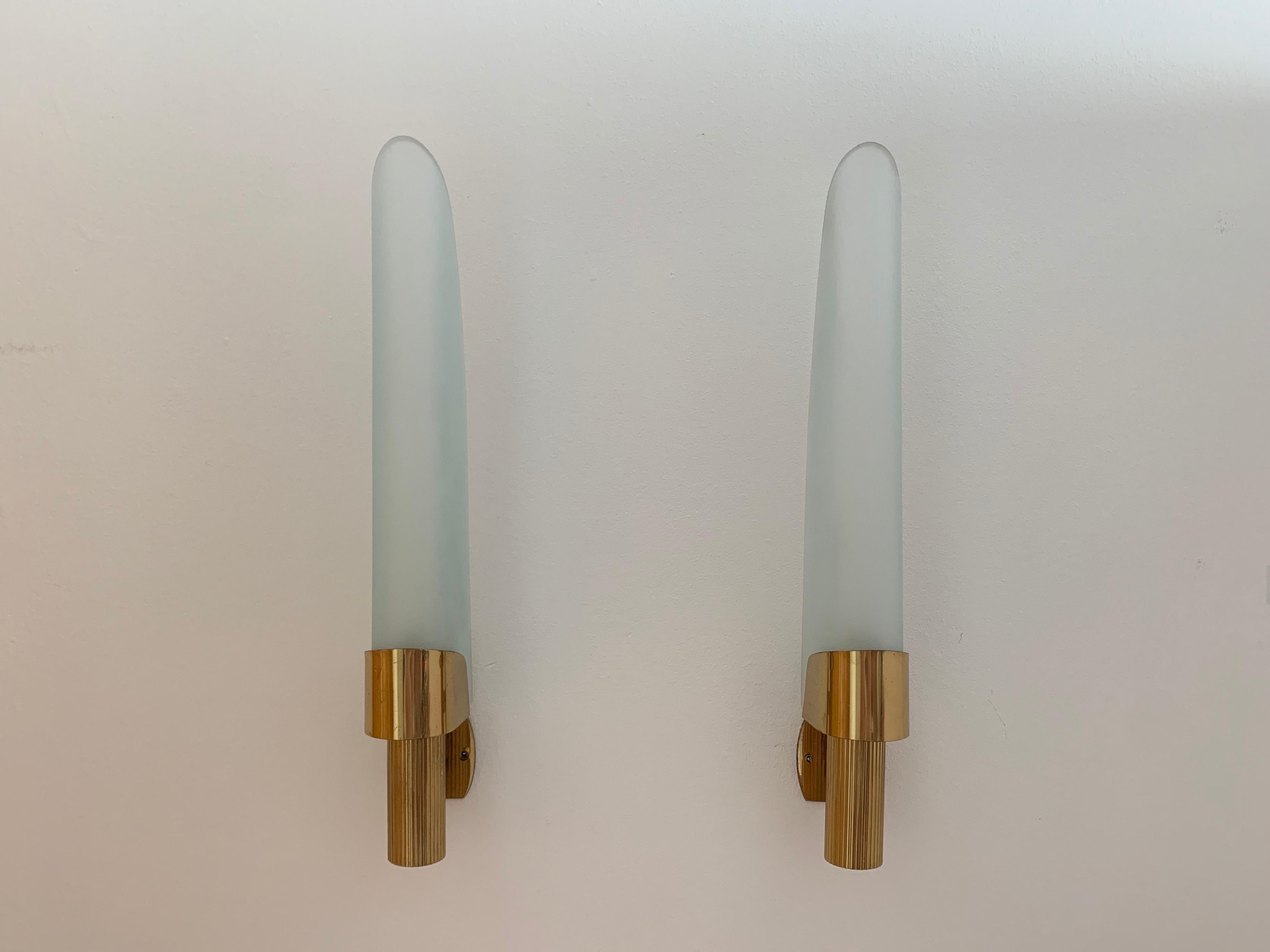 A set of 1960s sconces composer of aged golden brass ribbed fixtures holding large slightly frosted glass sheaths. Newly rewired. Fontana Arte Italy, 1960.