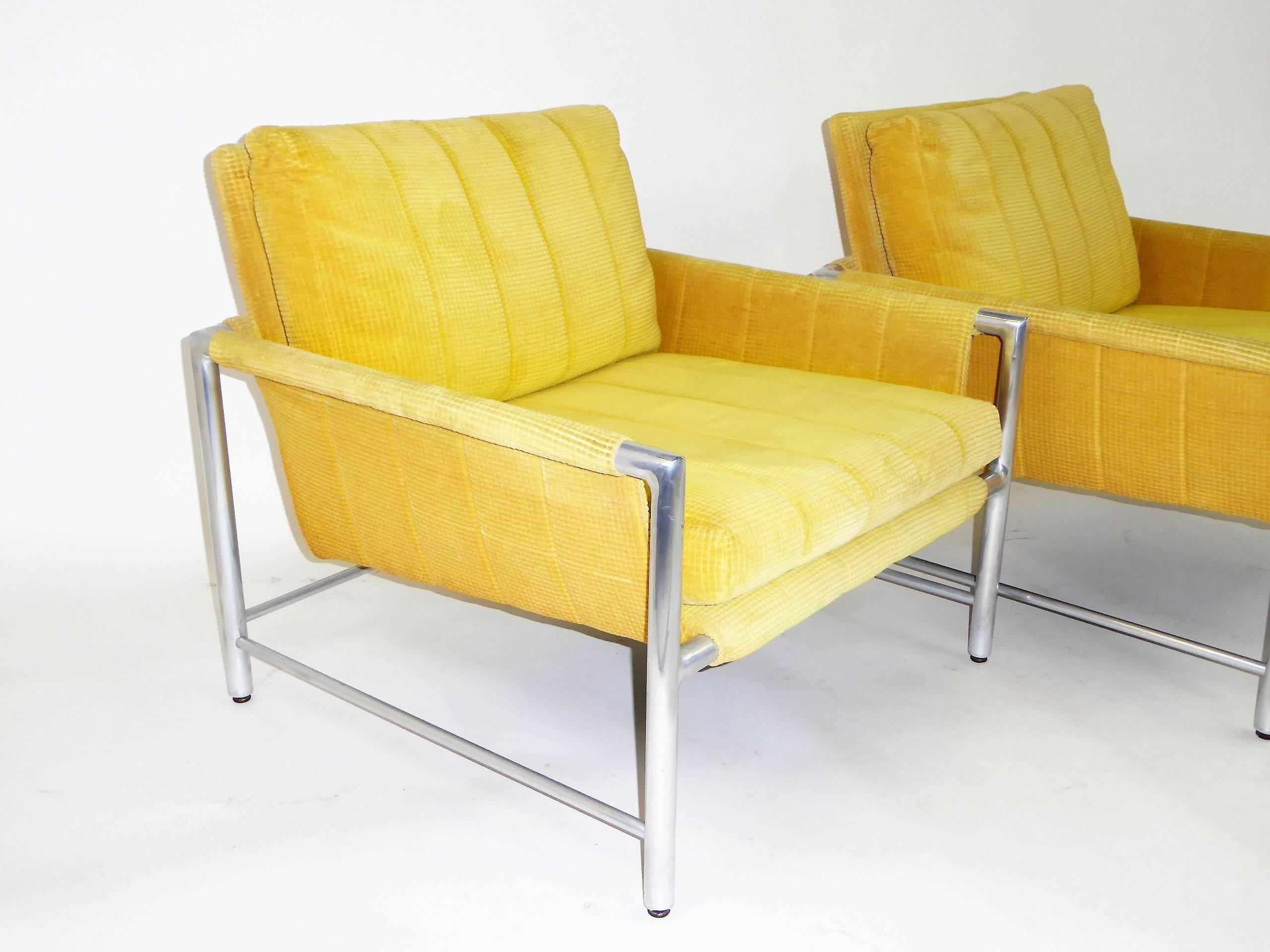 Here a pair of 1960s lounge chairs from Founder's Furniture with polished aluminium frames with a cushioned faux sling style ala Harvey Probber. Requiring new fabric, the original is a bright yellow chenille corduroy with staining. The pair retain