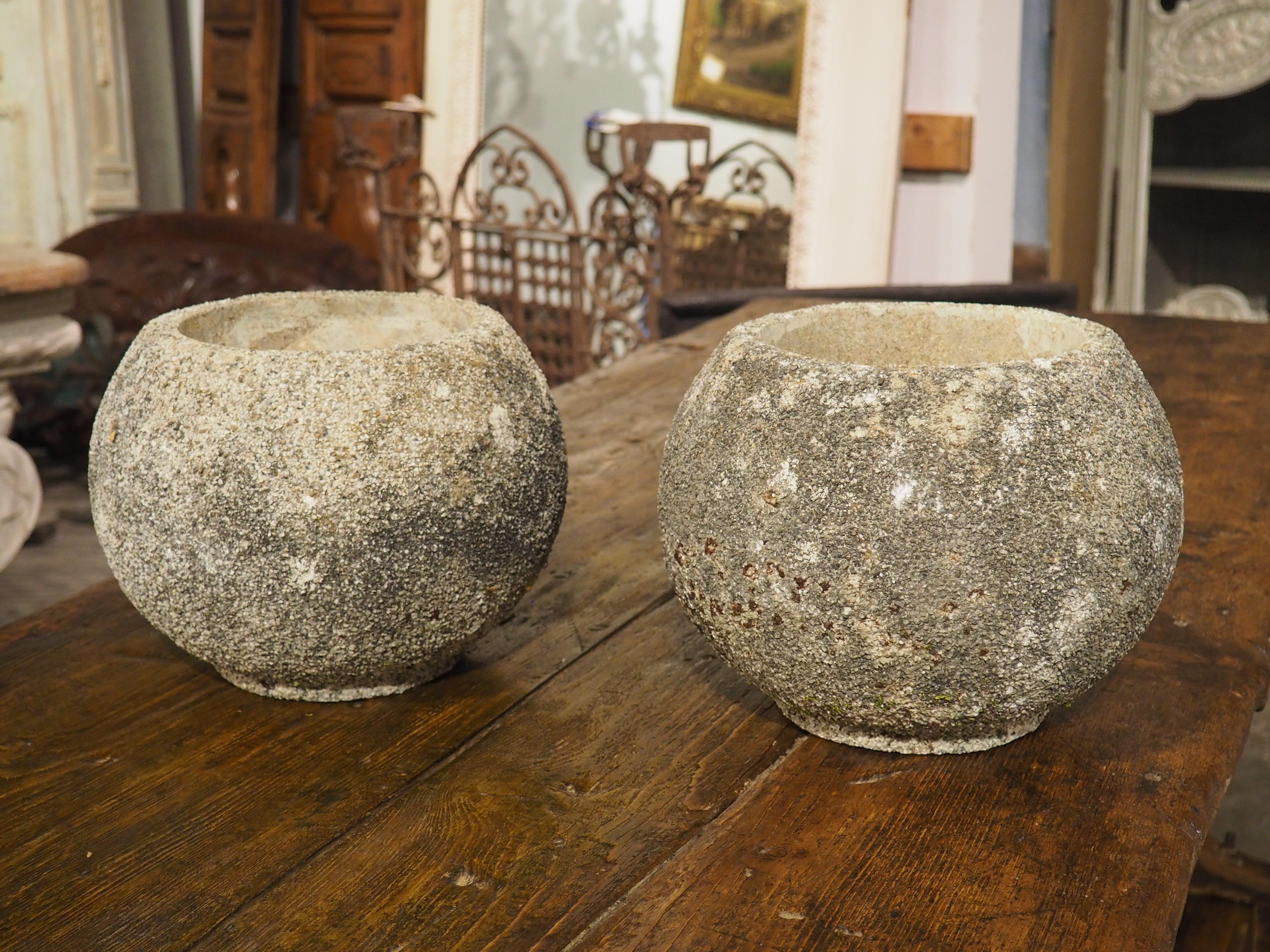 A fascinating and textured pair of planters, these French boule-form spherical jardinieres date to the 1960s. The cement main bodies are thick, about an inch deep, enhancing the crushed stone applique that gives the planters a multi-hued appearance
