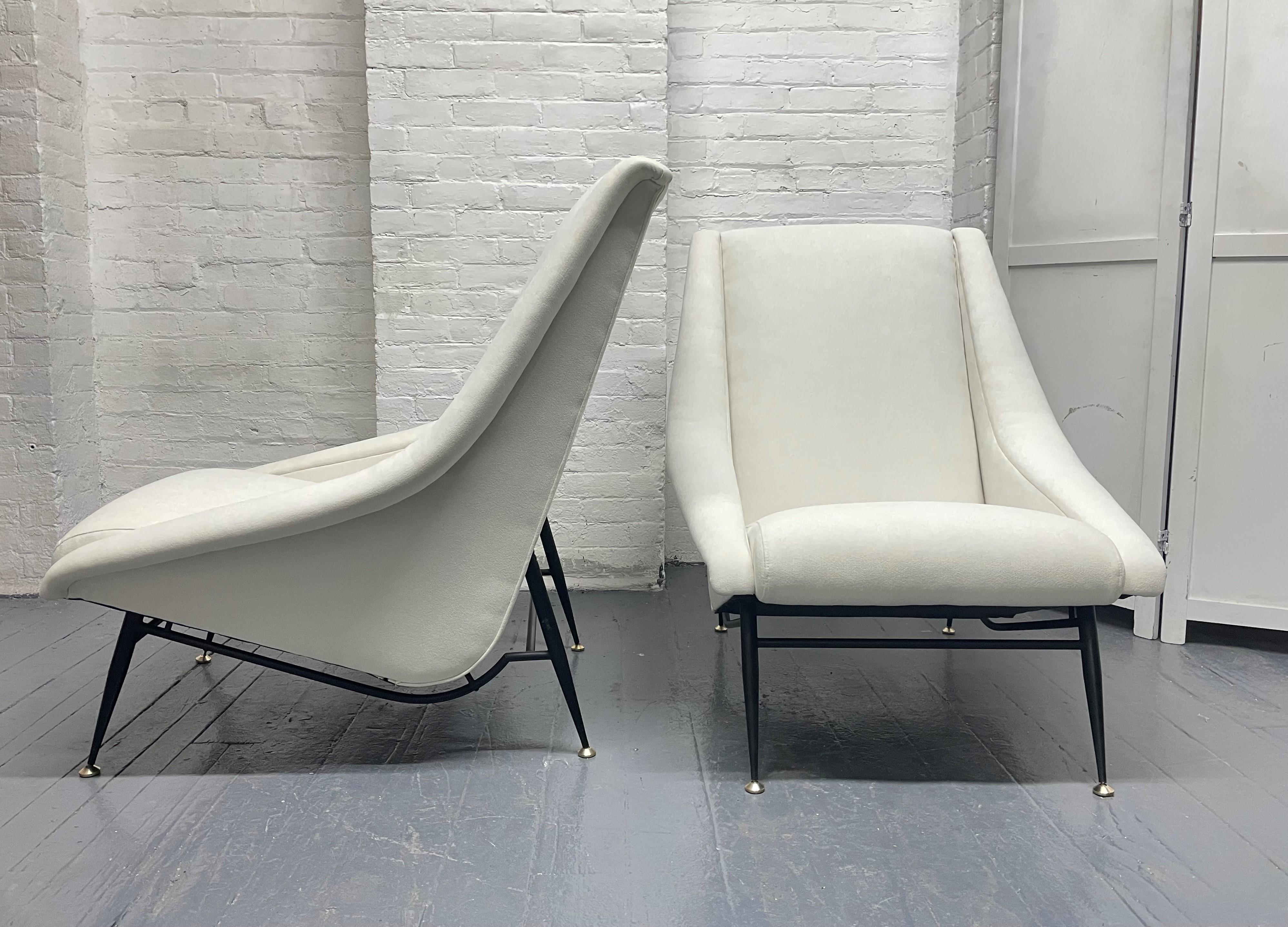 Pair of French lounge chairs by Henri Caillon for Erton. The chairs are upholstered in off-white fabric with enameled steel legs and brass feet. 

  