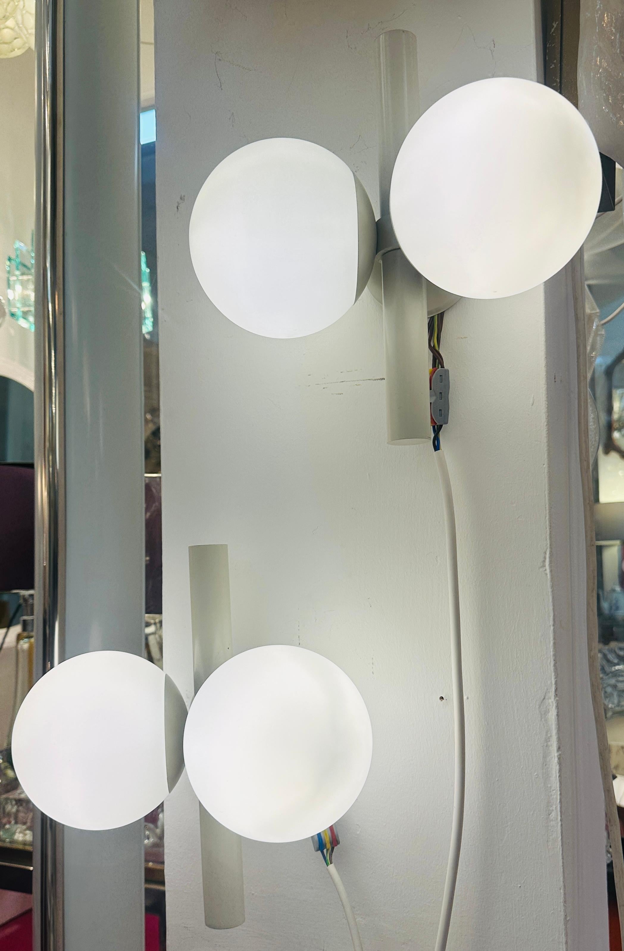 Pair of 1960s German Kaiser Leuchten space age wall lights or sconces.  

Each wall light features a pair of sputnik opaline glass globe shades on either side of an off-white lacquered tubular metal column.  The wall light is fixed to the wall with