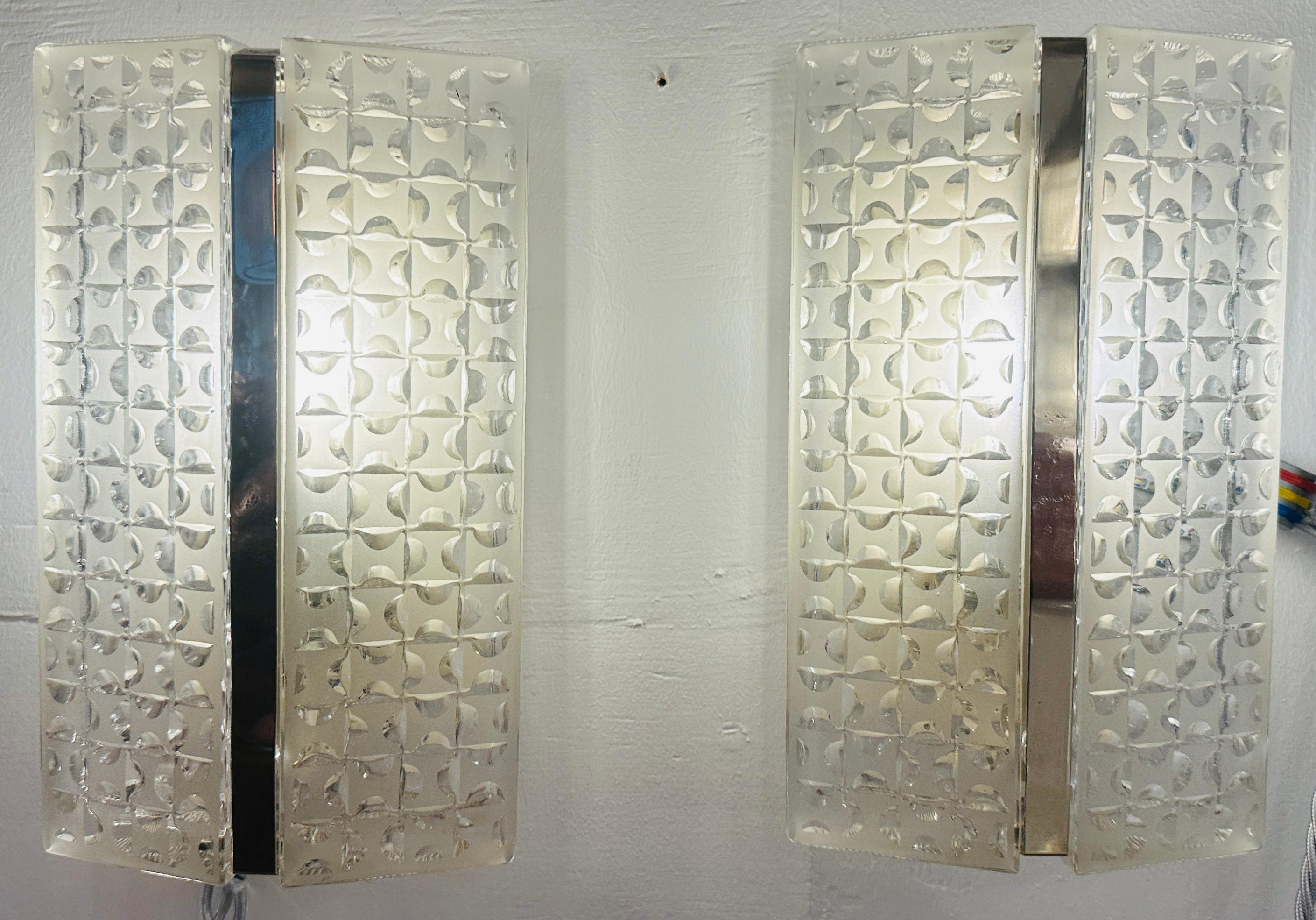 Coppia di applique geometriche smerigliate tedesche degli anni '60 con una striscia verticale cromata al centro.  Prodotto da Kaiser Leuchten. 
 
Il design geometrico in vetro smerigliato e trasparente, composto da piccoli quadrati con rientranze a