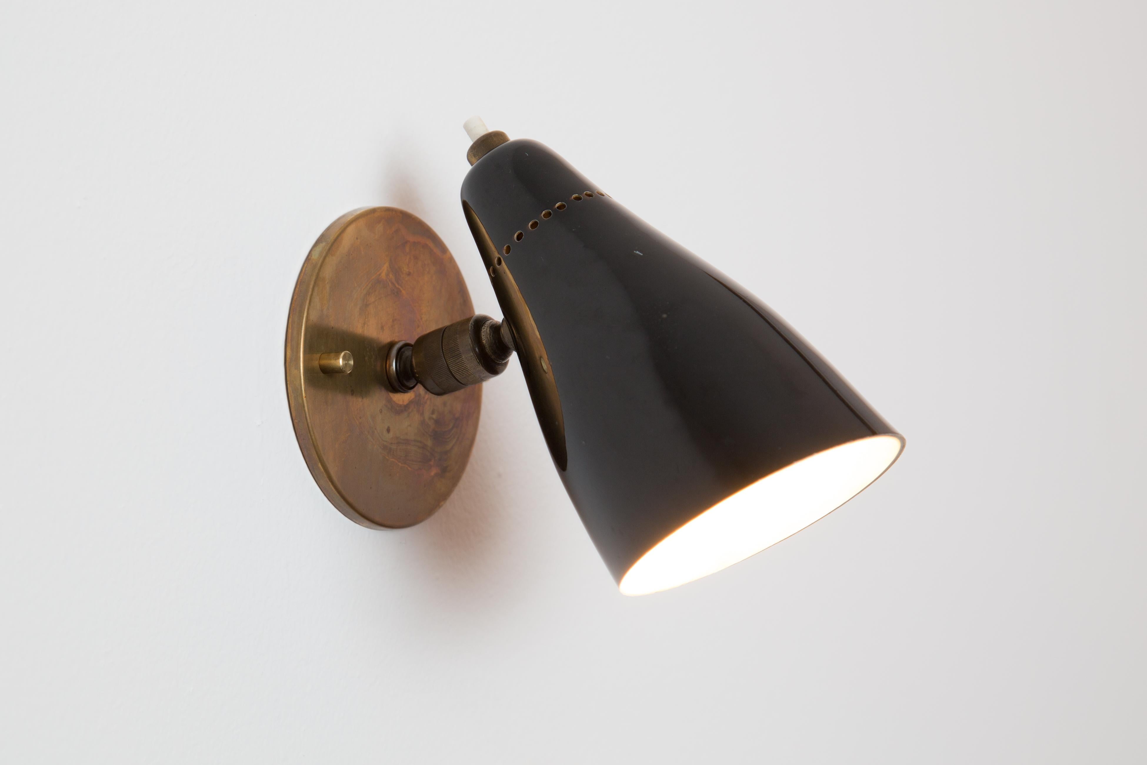 Pair of 1950s Giuseppe Ostuni Model #101 Black Articulating Sconces for O-Luce. Executed in patinated brass and black painted perforated aluminum shade. Sconces pivot up/down and left/right. An incredibly clean and refined design by one of the