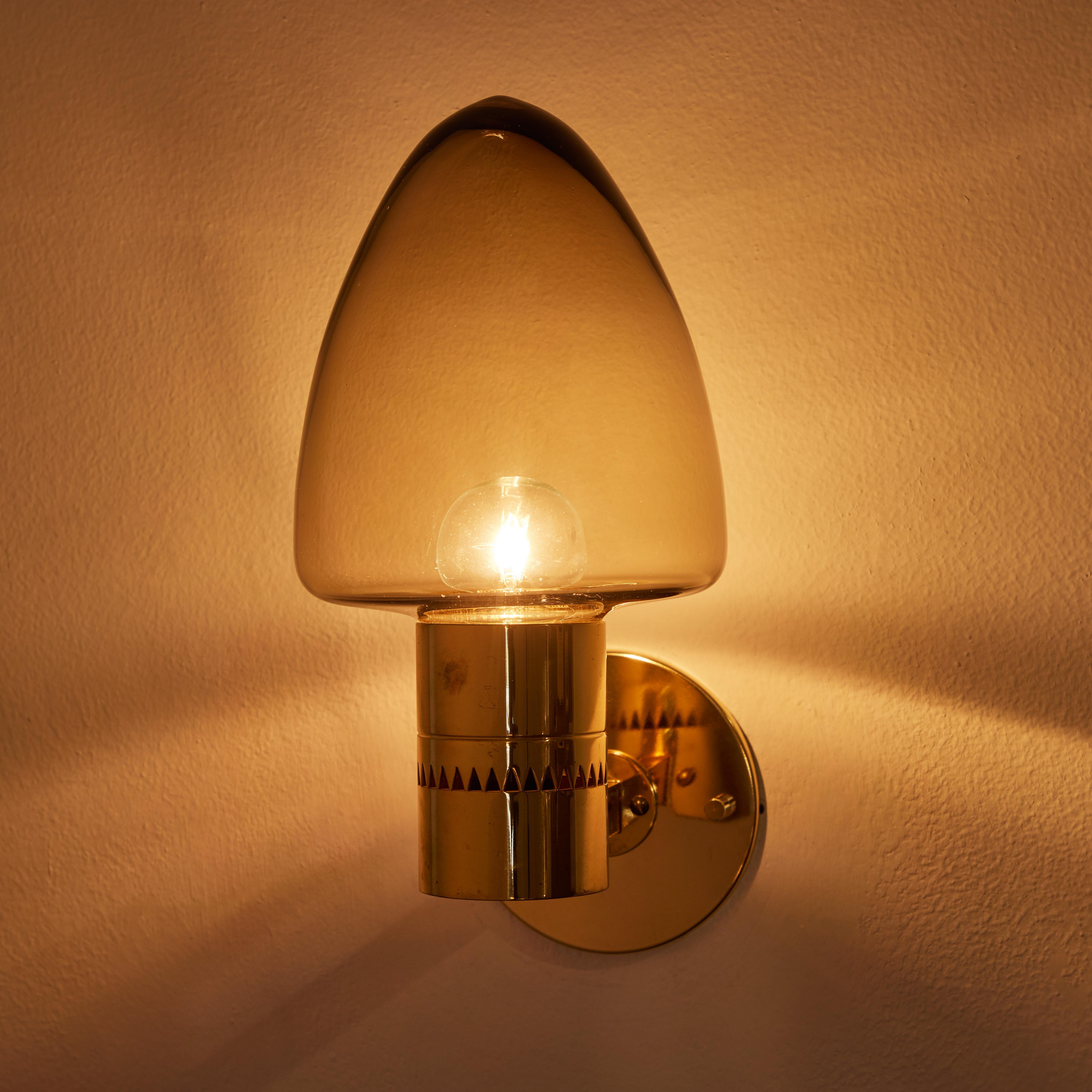 Pair of 1960s Hans-Agne Jakobsson Model V-220 brass & glass sconces for Markaryd. An incredibly refined vintage design that is quintessentially Swedish. Executed in sculpturally bent brass and blown smoked glass.

Price is for the pair.

Rewired