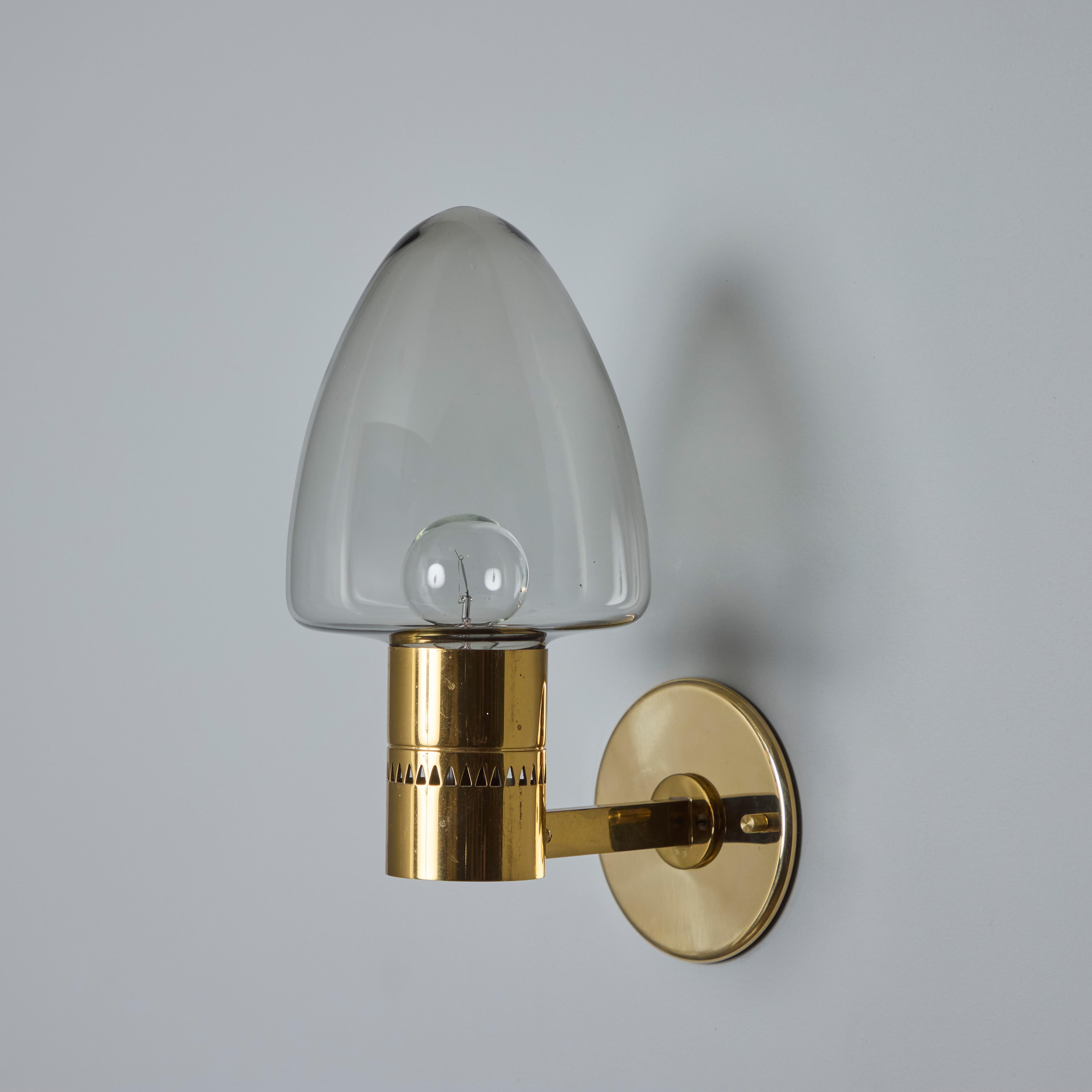 Paire d'appliques en laiton et verre modèle V-220 de Hans-Agne Jakobsson des années 1960 pour Markaryd. Un design vintage incroyablement raffiné, typiquement suédois. Exécuté en laiton plié de manière sculpturale et en verre fumé soufflé.

Le prix