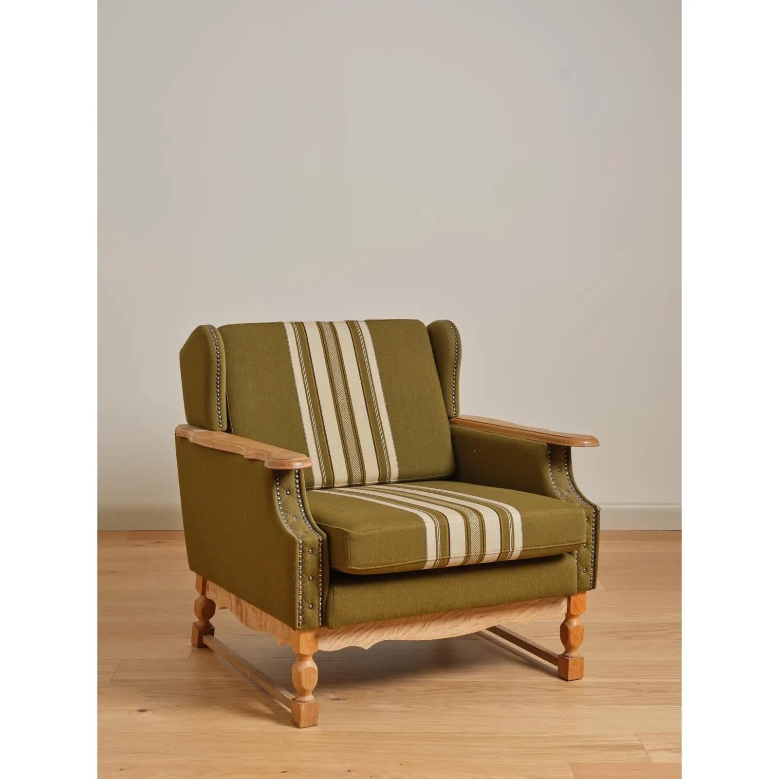 Pair of lounge chairs in oak and traditional woven fabric; featuring winged backs, paddle-style arms, and sculpted urn-and-block legs. Attributed to Henning (Herny) Kjaernulf; Denmark, c. 1960's.

Small tears to corners at front stiles on both