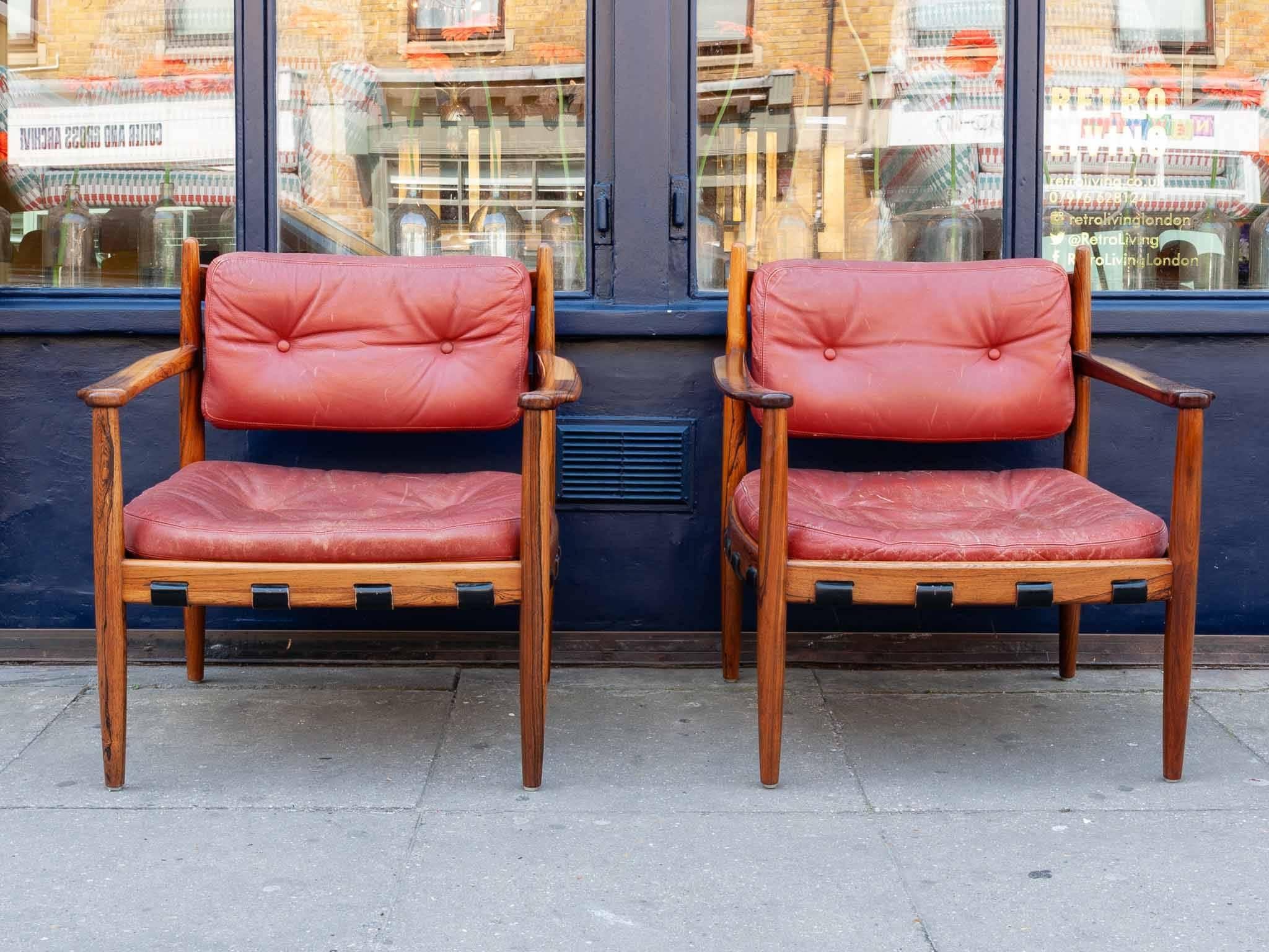 A pair of 1960s Swedish Rosewood and red leather upholstered armchairs produced by Ire Mobler in Skillingaryd. Labelled. These Cadett armchairs designed by Eric Merthen in solid rosewood. In very good vintage condition with some wear to the leather