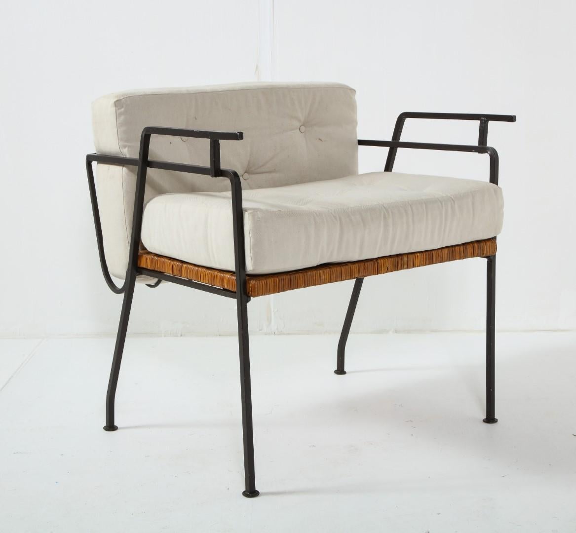 A pair of 1960s wrought iron and cane lounge chairs by Maurizio Tempestini for Salterini. Architectural design with woven rattan and metal elements and tufted white seat and back cushions.