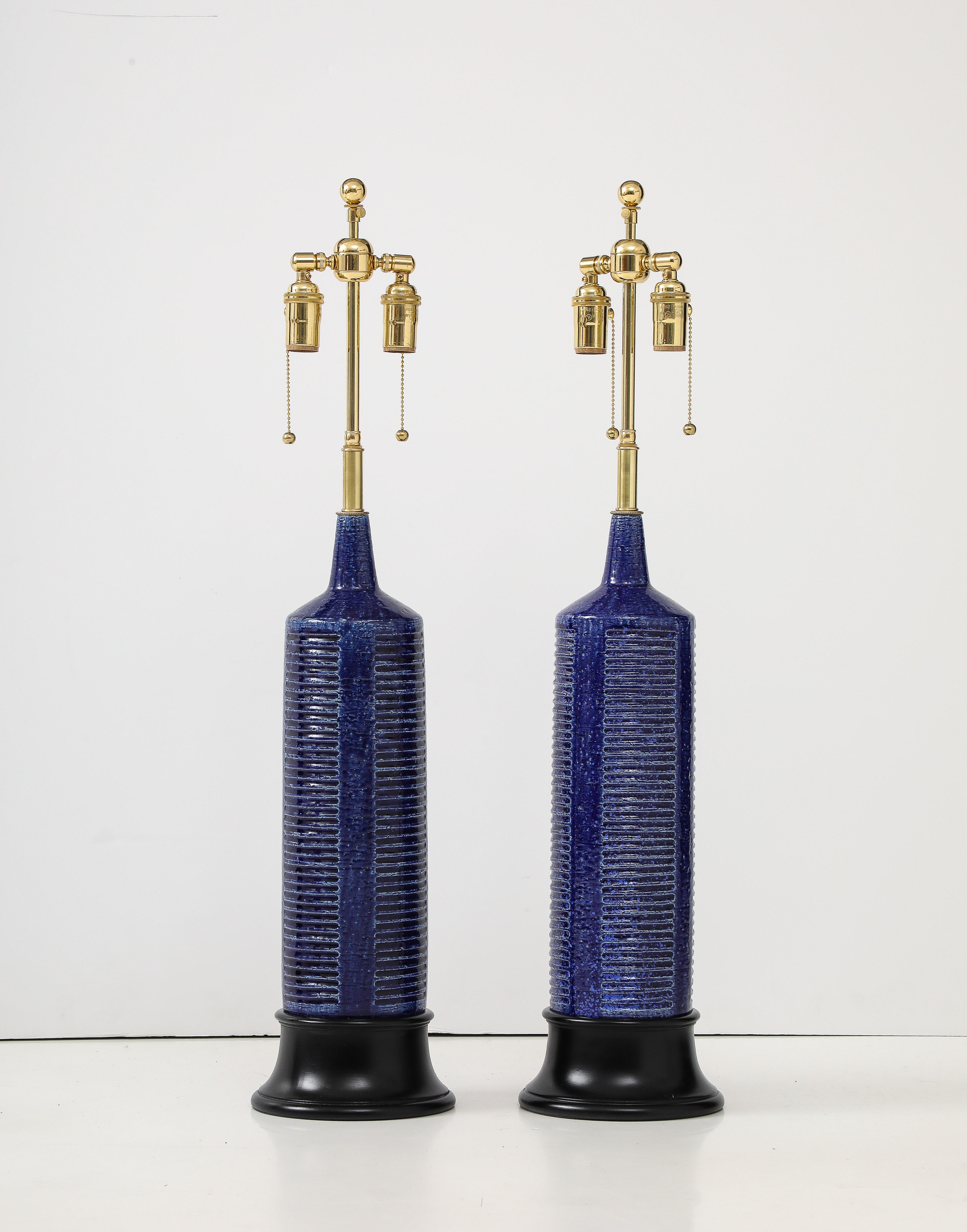 Beautiful pair of 1960's Italian ceramic lamps.
The cylindrical lamp body has a ribbed design pattern and a wonderful 
cobalt blue glaze finish.
The lamps have been Newly rewired for the US with adjustable polished brass
double clusters that take