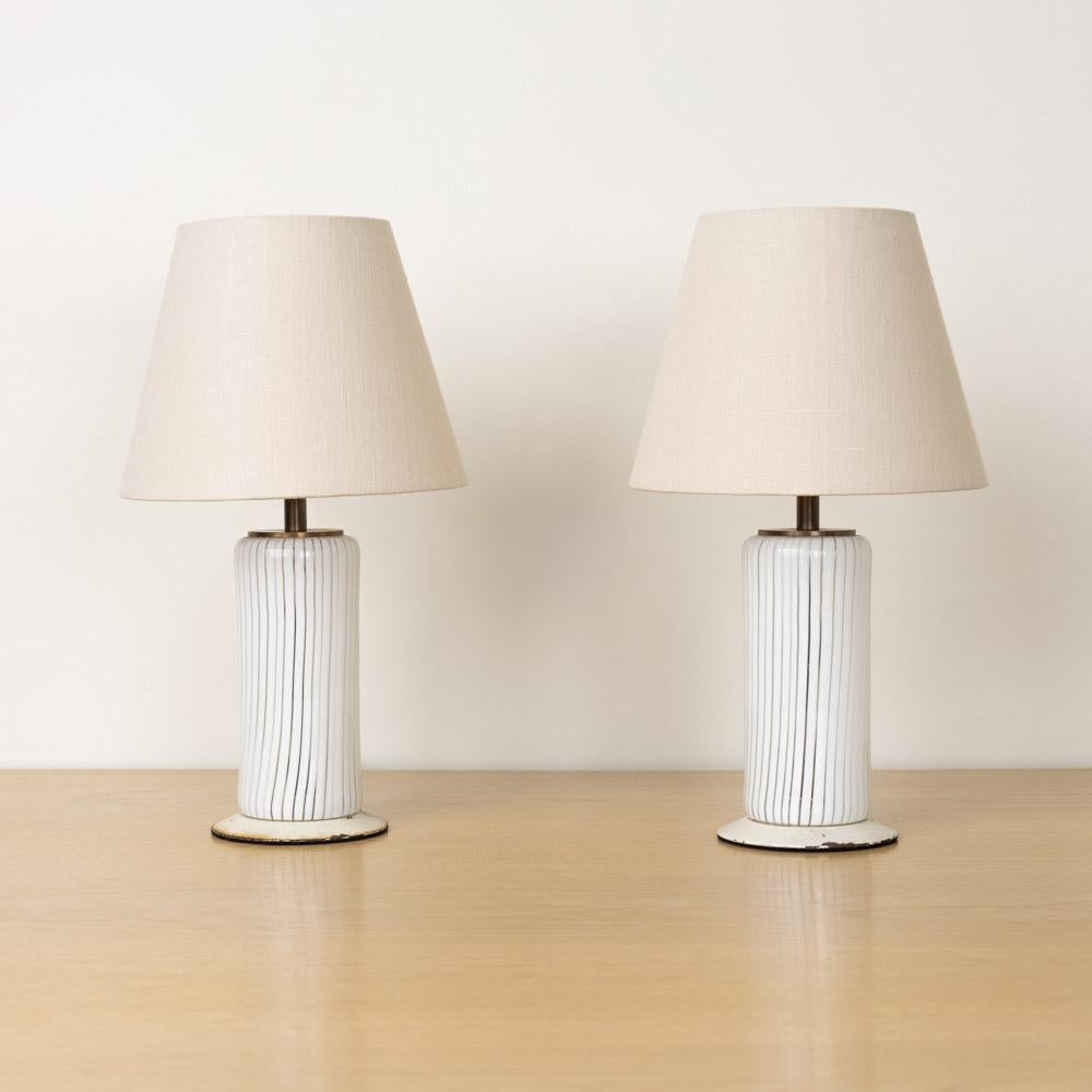 Incroyable paire de lampes de table en verre d'Italie, années 1960. Corps en verre avec détails rayés blancs sur une base circulaire en métal peint en blanc. Câblage refait à neuf et nouveaux abat-jour en lin. La finition métallique d'origine