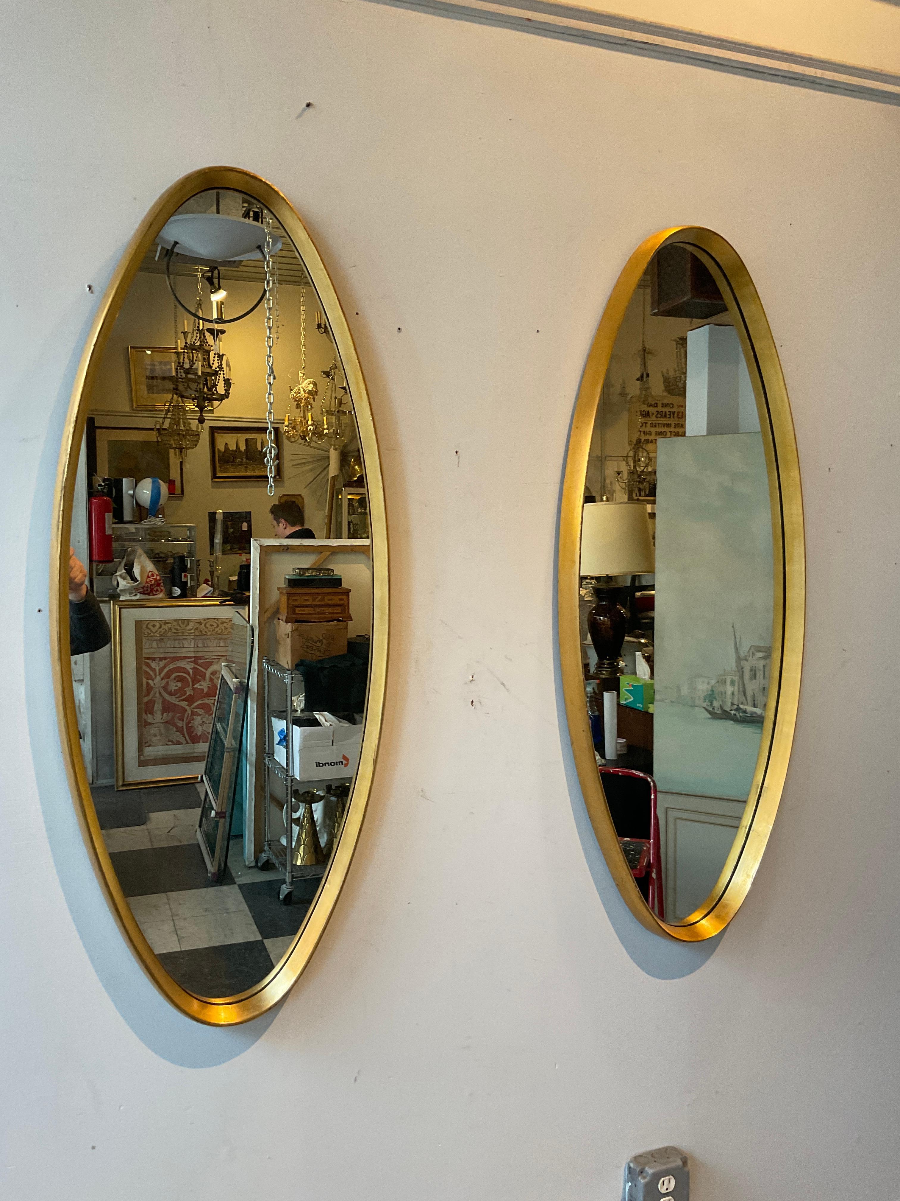 Pair of 1950s Italian oval gilt wood deep framed mirrors.