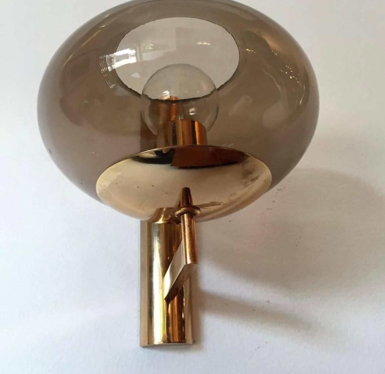 A pair of polished brass Italian wall lights with smoked glass globe shades designed by Gaetano Sciolari. Newly Rewired.
