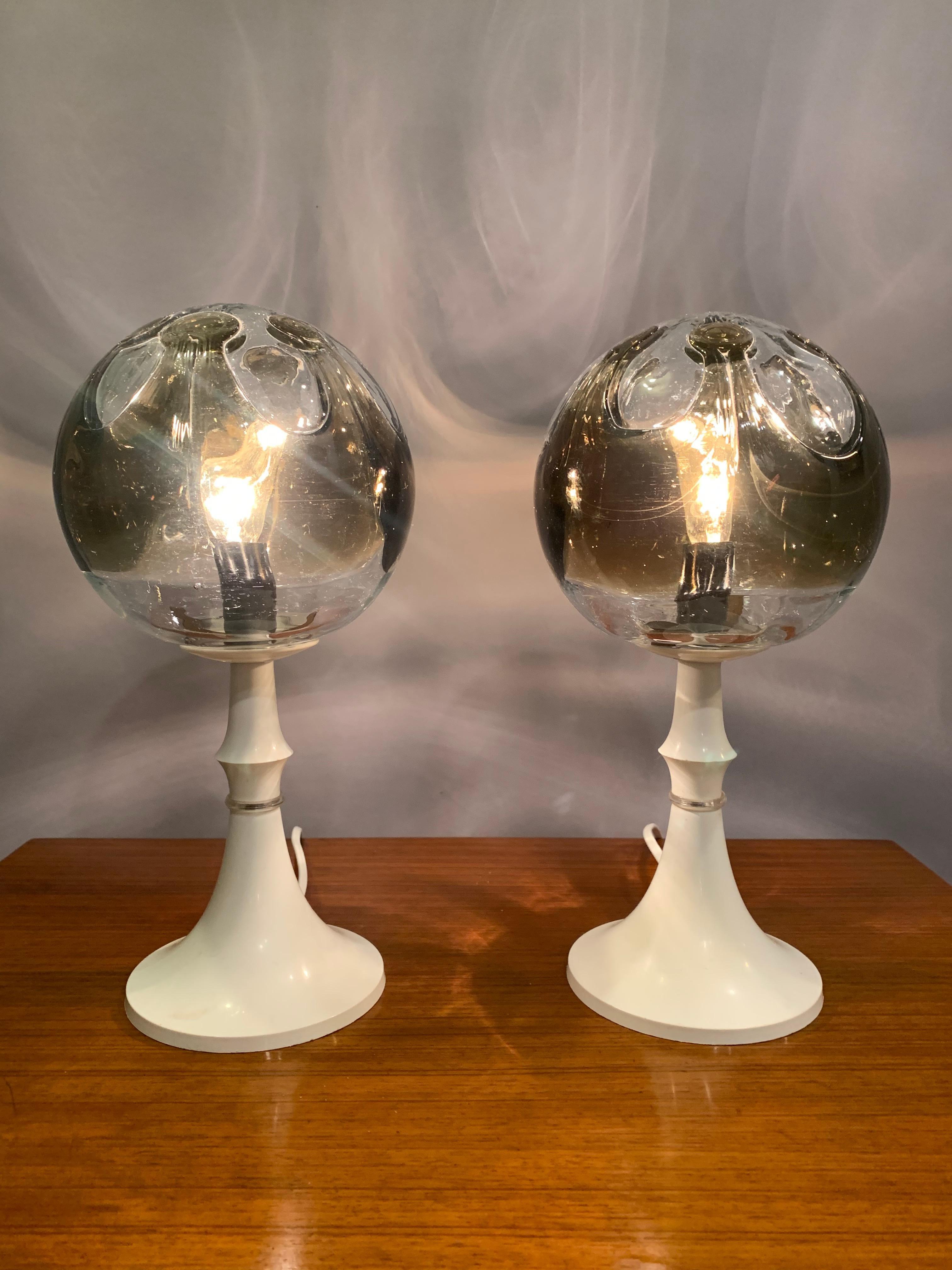 An unusual and rare pair of highly decorative 1960s Kaiser Leuchten table lamps in very good vintage condition. A single hand blown Mazzega clear crystal and smoked glass globe sits on a white plastic formed conical base. Some small signs of age