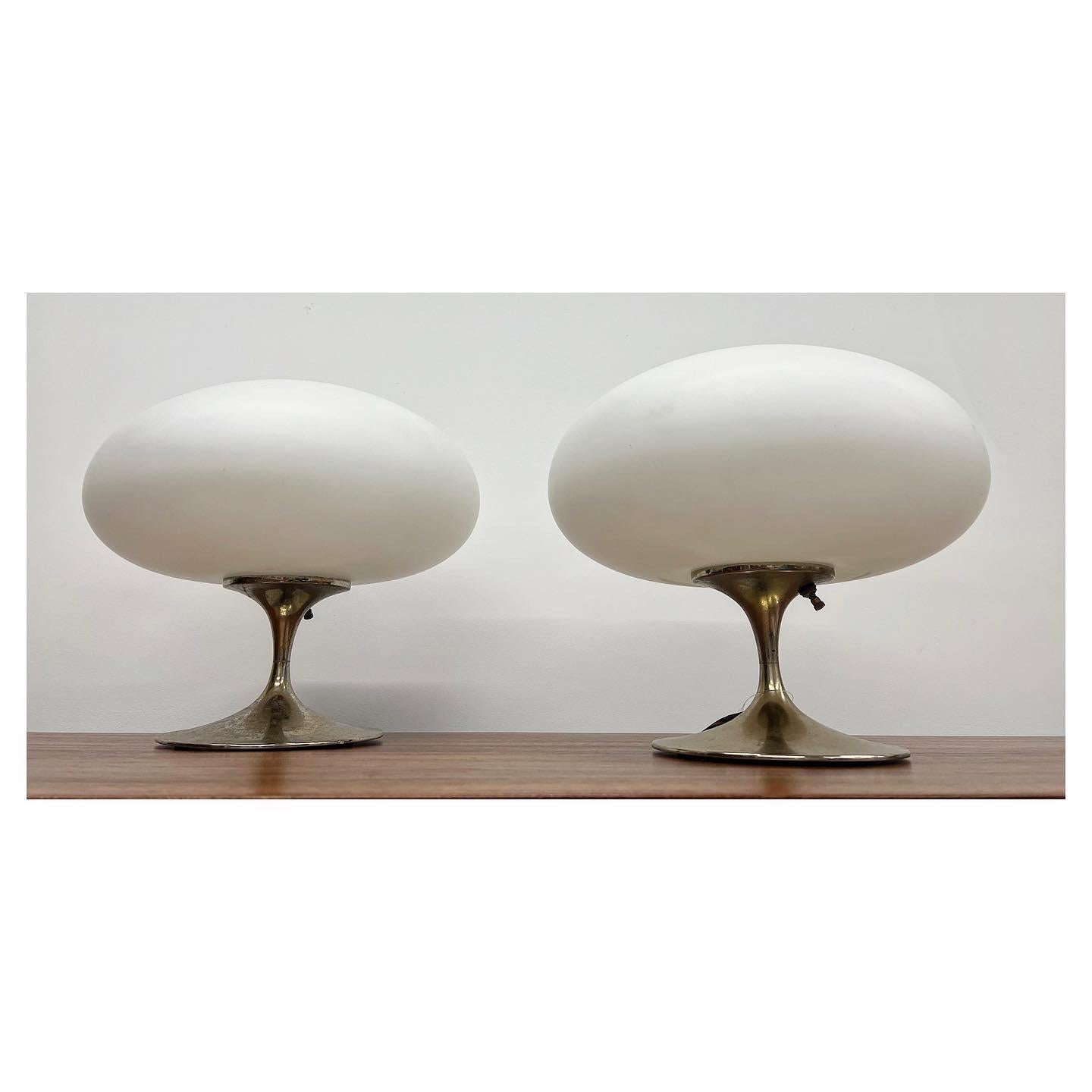 Gorgeous pair of lamps made by Laurel Lamp Company circa 1960s. These “mushroom” lamps have a glass topper shade that when illuminated, casts a beautiful glow. The pedestal base is brass and does exhibit patina, but appropriate with the age. They