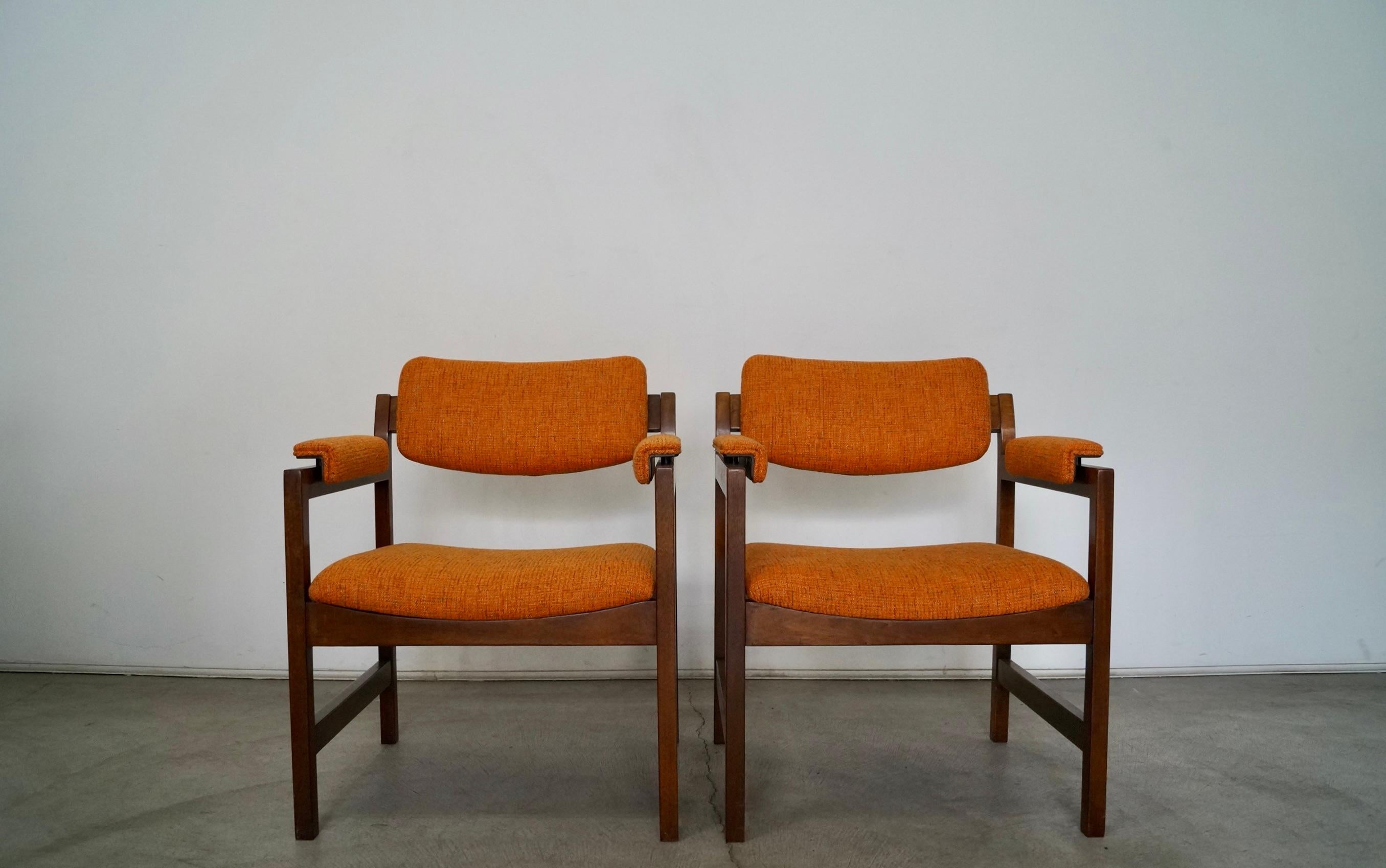 Vintage 1960s Mid-Century Modern pair of armchairs for sale. The frames are solid mahogany in a walnut finish, and they have been reupholstered in new fabric and foam. The fabric we selected is Knoll Textiles Diva line in Saffron that goes for