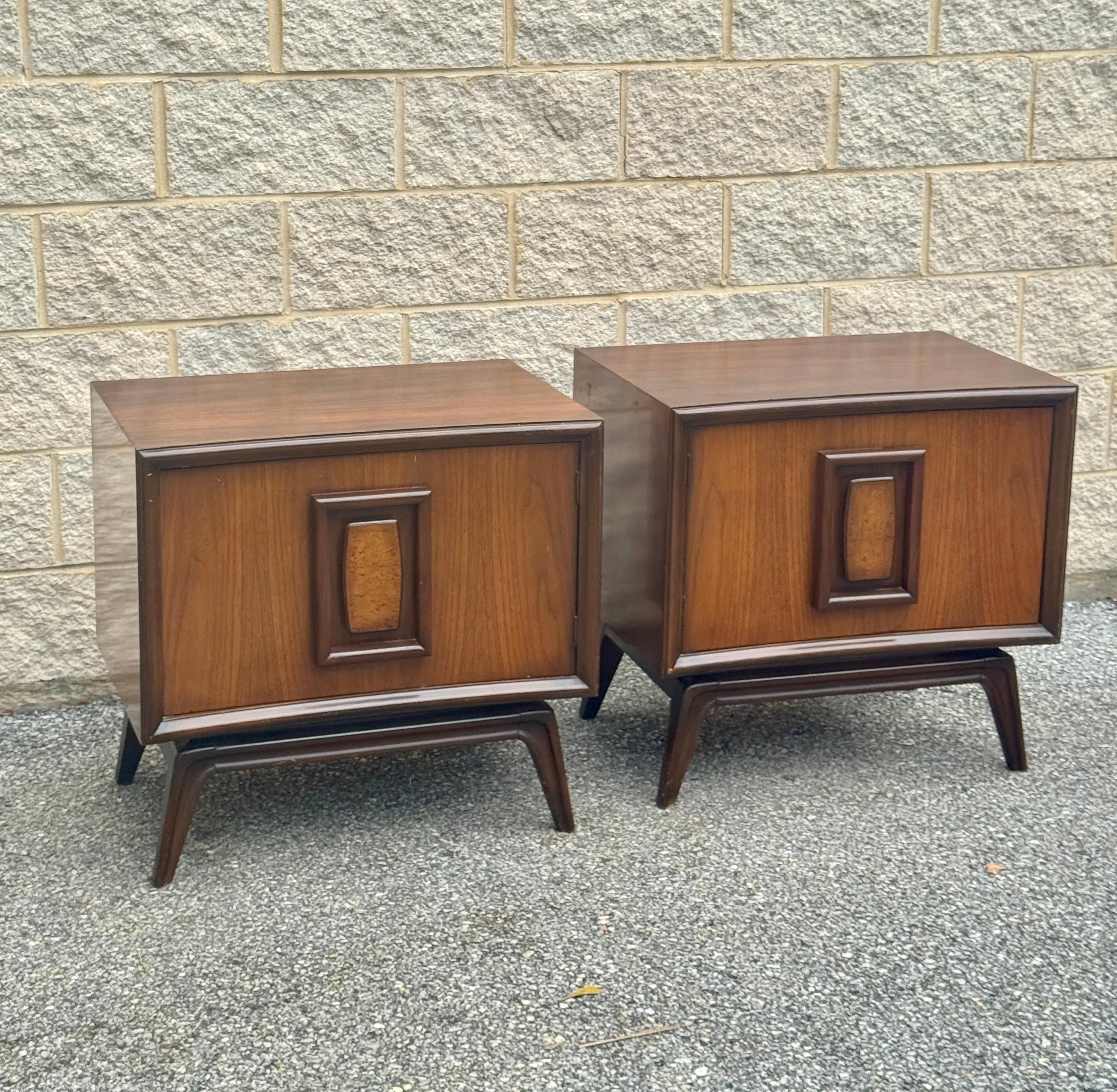 Paire raffinée de tables de nuit en noyer du milieu du siècle dernier des années 1960, aux lignes épurées et aux portes à panneaux encastrés encadrés. Chaque armoire s'ouvre sur un intérieur spacieux, idéal pour le rangement au chevet du lit ou dans