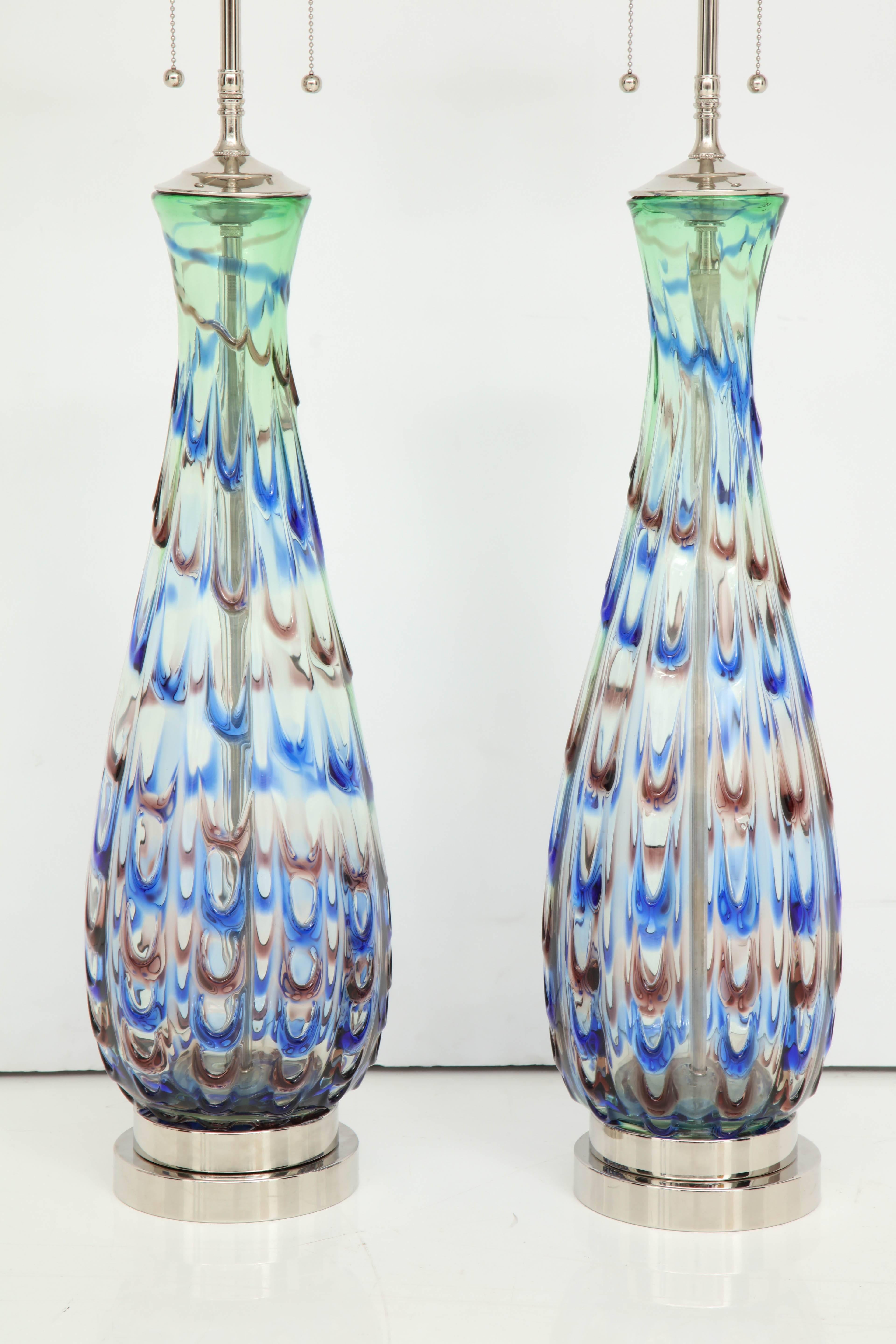 Beautiful pair of 1960s Murano glass lamps with a feathered design pattern.
The clear glass lamp bodies have a feathered design of blue, green and red and they are mounted on double stacked polished nickel bases.
The lamps have been newly rewired