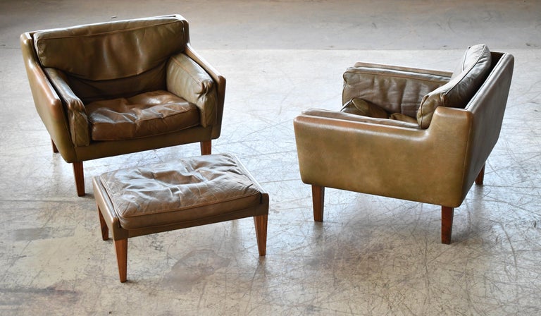 Fantastic leather chairs with ottoman in olive brown buffalo leather raised on rosewood legs. This rare model which resembles the fabled model V11 was designed by Illum Wikkelsø and manufactured by Holger Christiansen in Denmark in the 1960s. Low