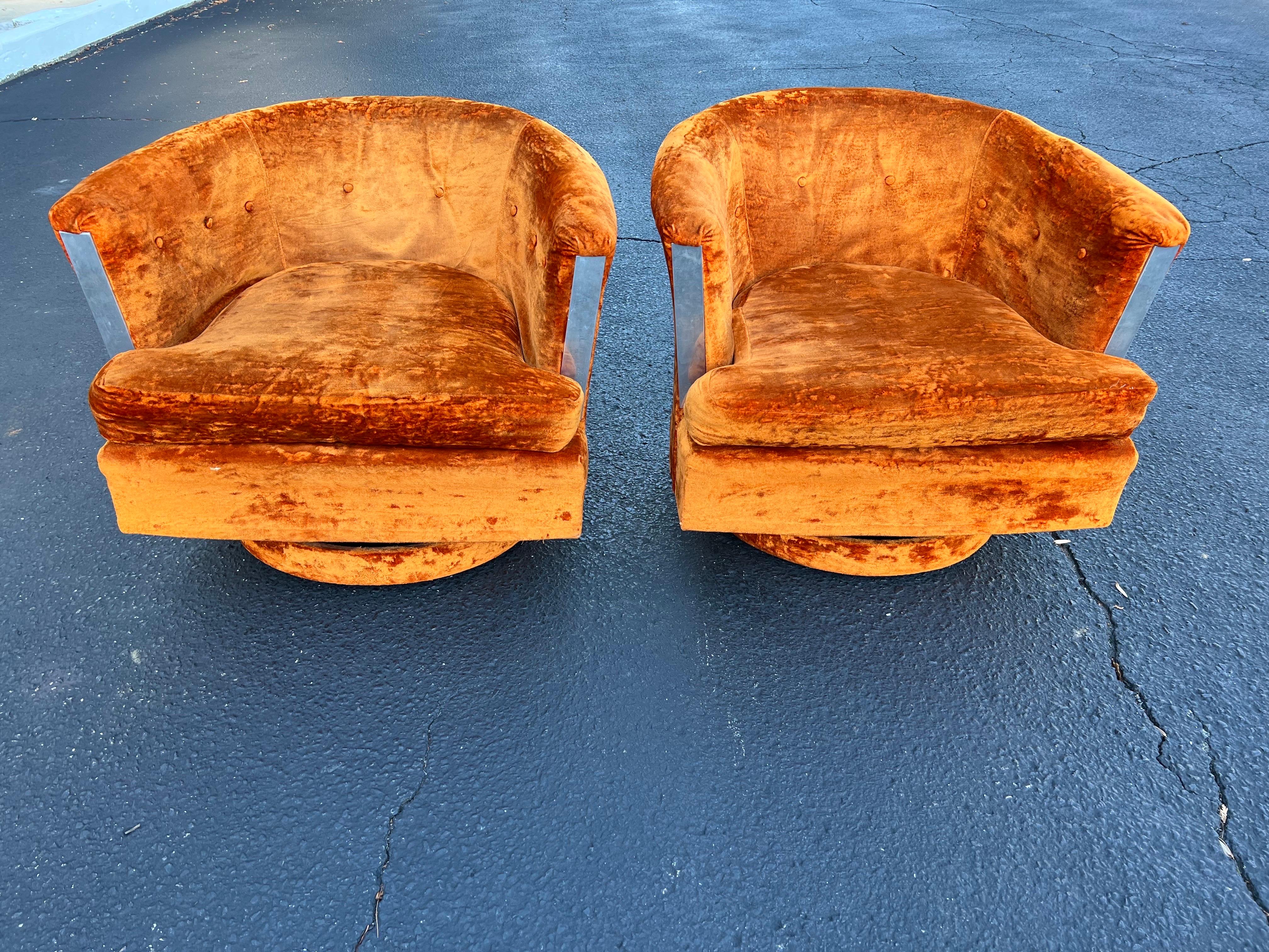 Pair of 1960’s Orange Crushed Velvet Swivel Chairs. Super mod pair of chairs with chrome trim on front. Groovy swivel pair by Singer. Perfect for that sunken living room with shag carpet. Perfect for a period piece for a set designer.
