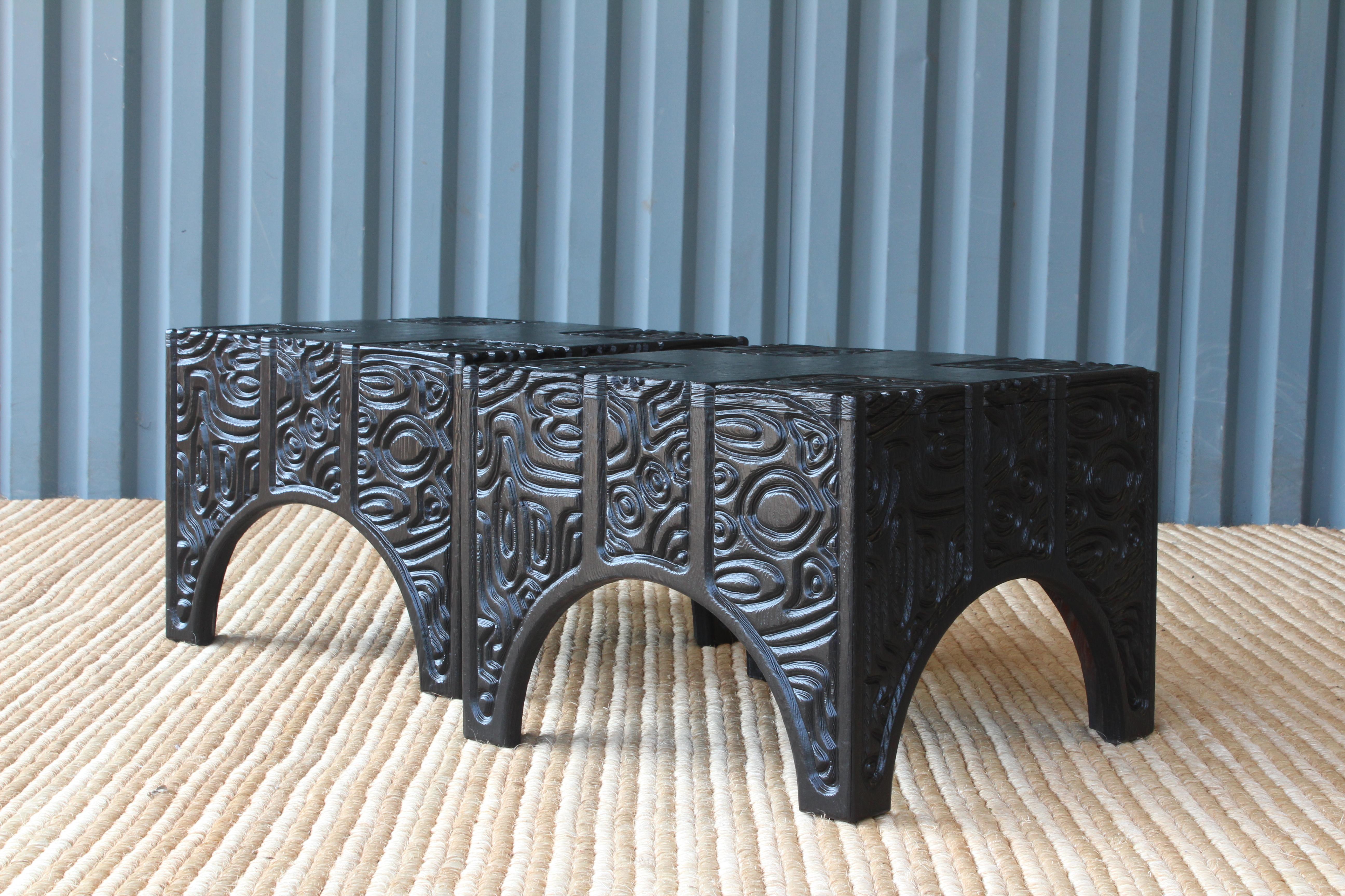 Pair of rare and unusual panel carved end tables by Sherrill Broudy, in the style of Witco. The pair have been professionally refinished in satin black. Sold as a pair.