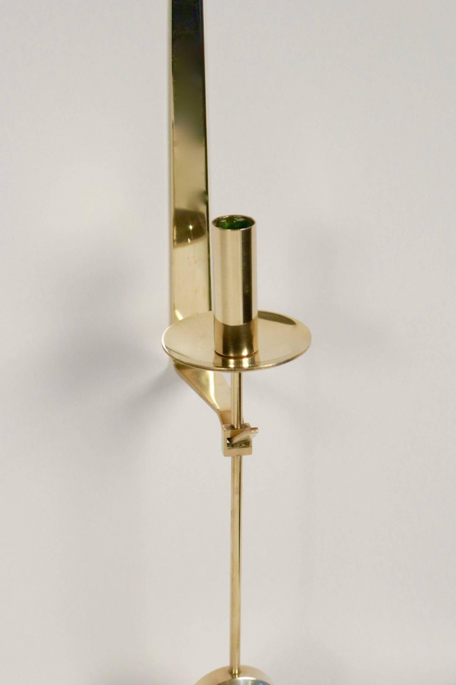 
Composed of an elegant brass plate of trapezoidal shape forming a right angle on the lower part.
At the end of the plate of the lower part, it receives the candlestick underlined by a cup and a pendulum on the lower part. 

 