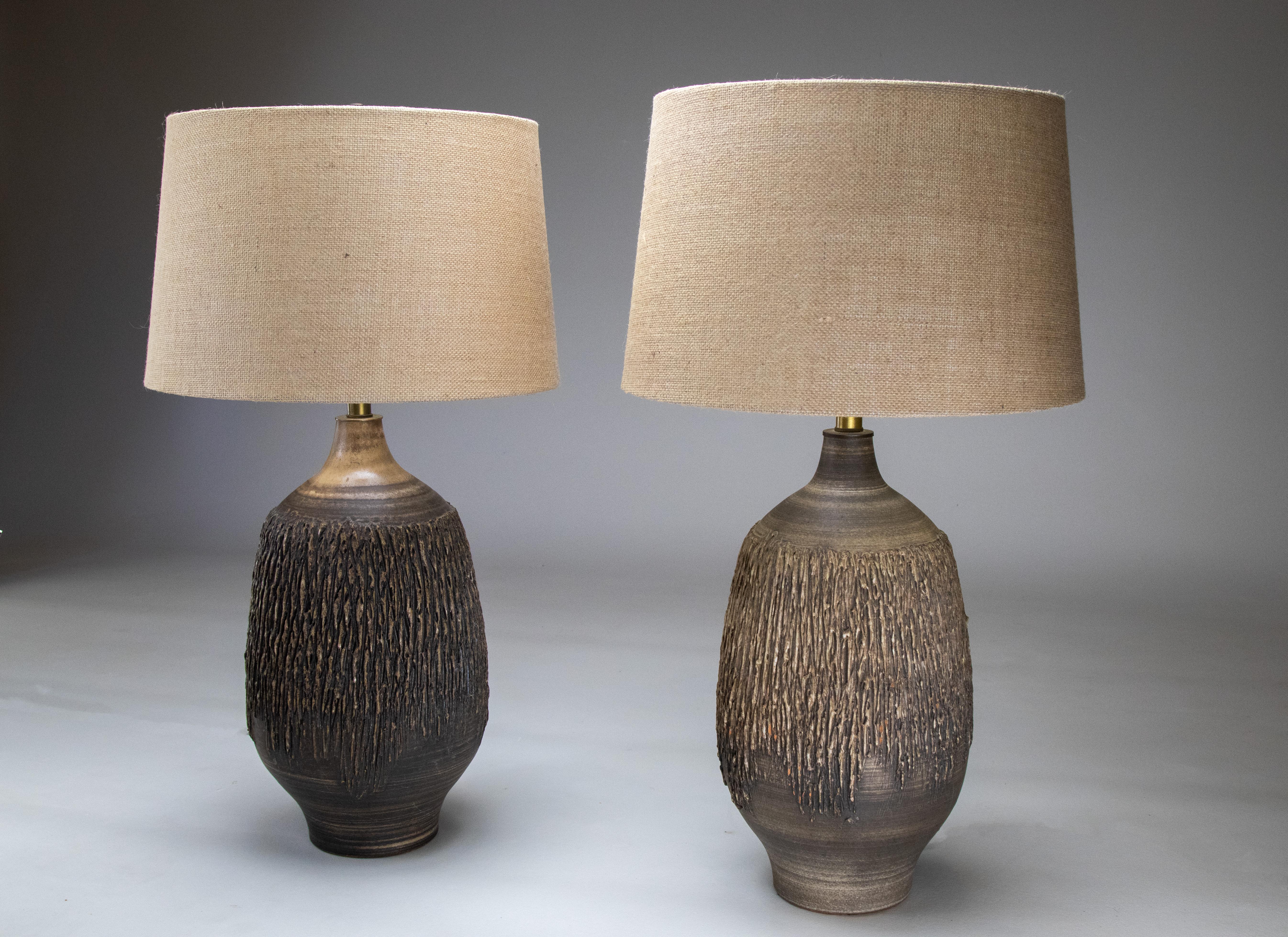 A pair of large scale textured ceramic lamps designed by Lee Rosen and manufactured by Design Technics. This is a mated pair with one lamp having a darker glaze than the other. On opposite sides of a bed or in high light situations it is not that