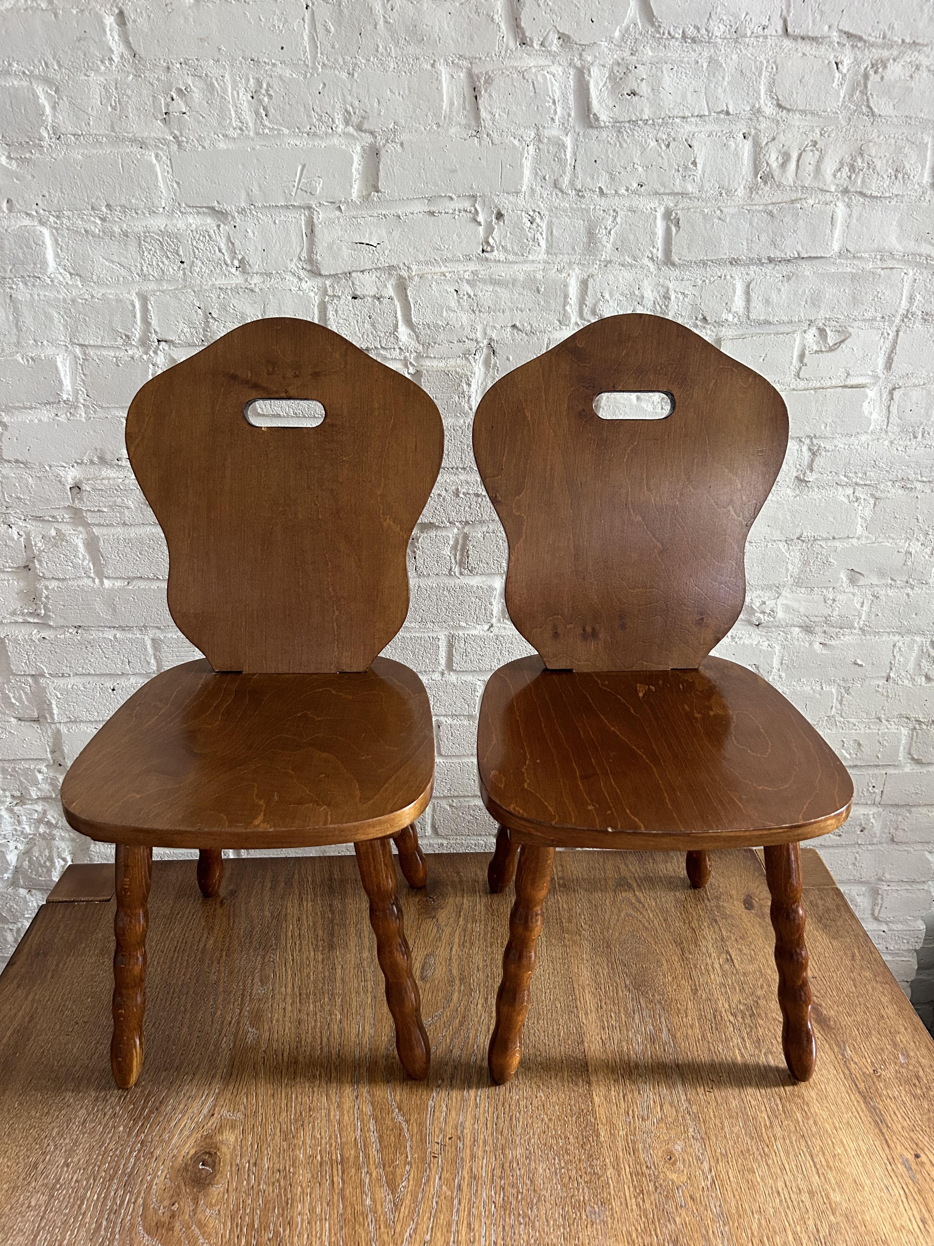 Pair of two adorable solid wood children's chairs. Features a carved solid back and seat atop four turned legs. While originally a children's chair, they would be best now as a decorative stool in a living room, entry way, bedroom or bathroom. The