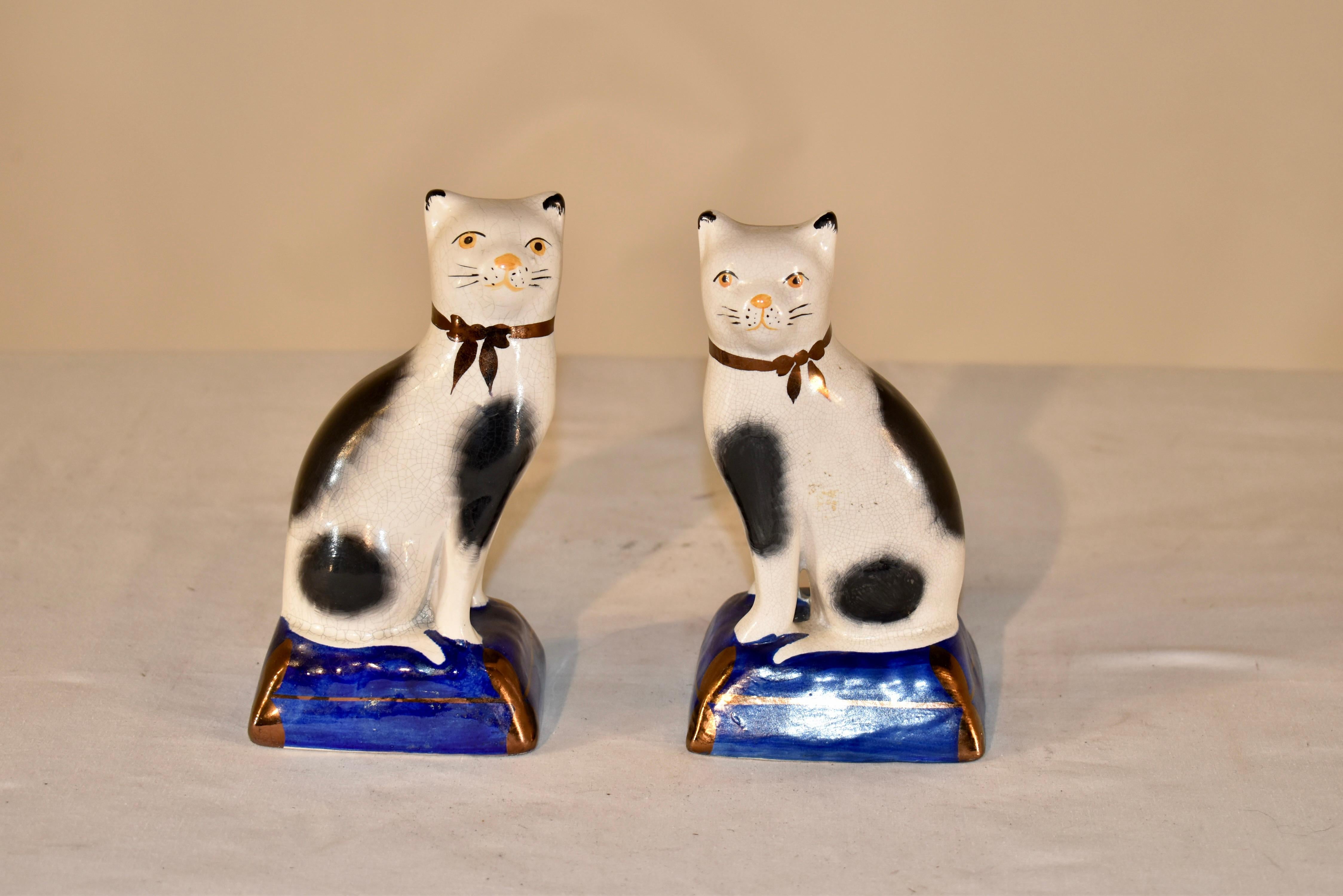 Pair of lovely Staffordshire cat figures with separated front legs, supported on cobalt blue bases.  The cats are hand-painted in black and white, with black tipped ears.  Such a darling pair!
