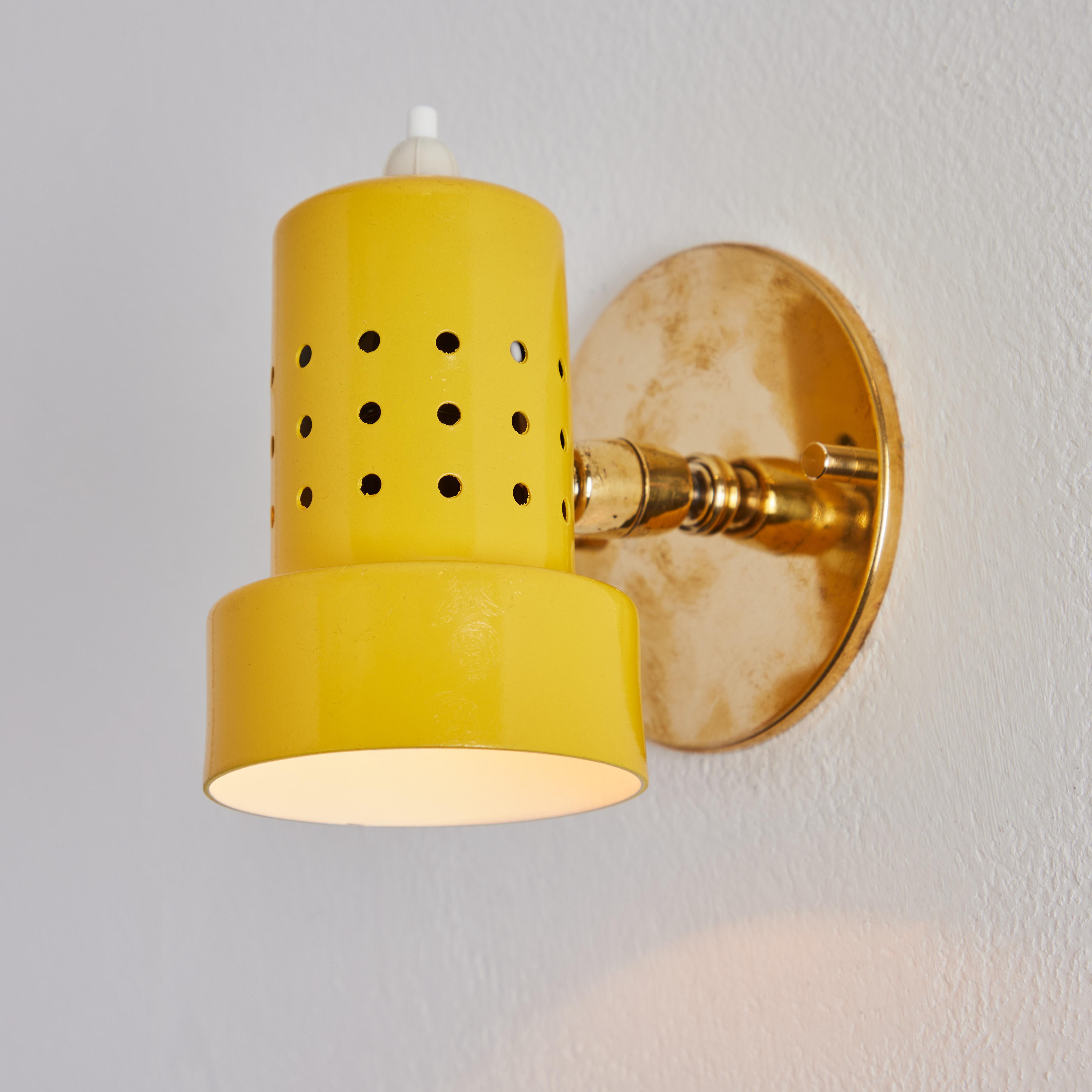 Pair of 1960s Stilux Milano perforated yellow articulating sconces. Executed in brass and yellow painted metal. These highly adjustable sconces pivot up/down and rotate left/right on a ball joint. Wired for US electrical with custom period style