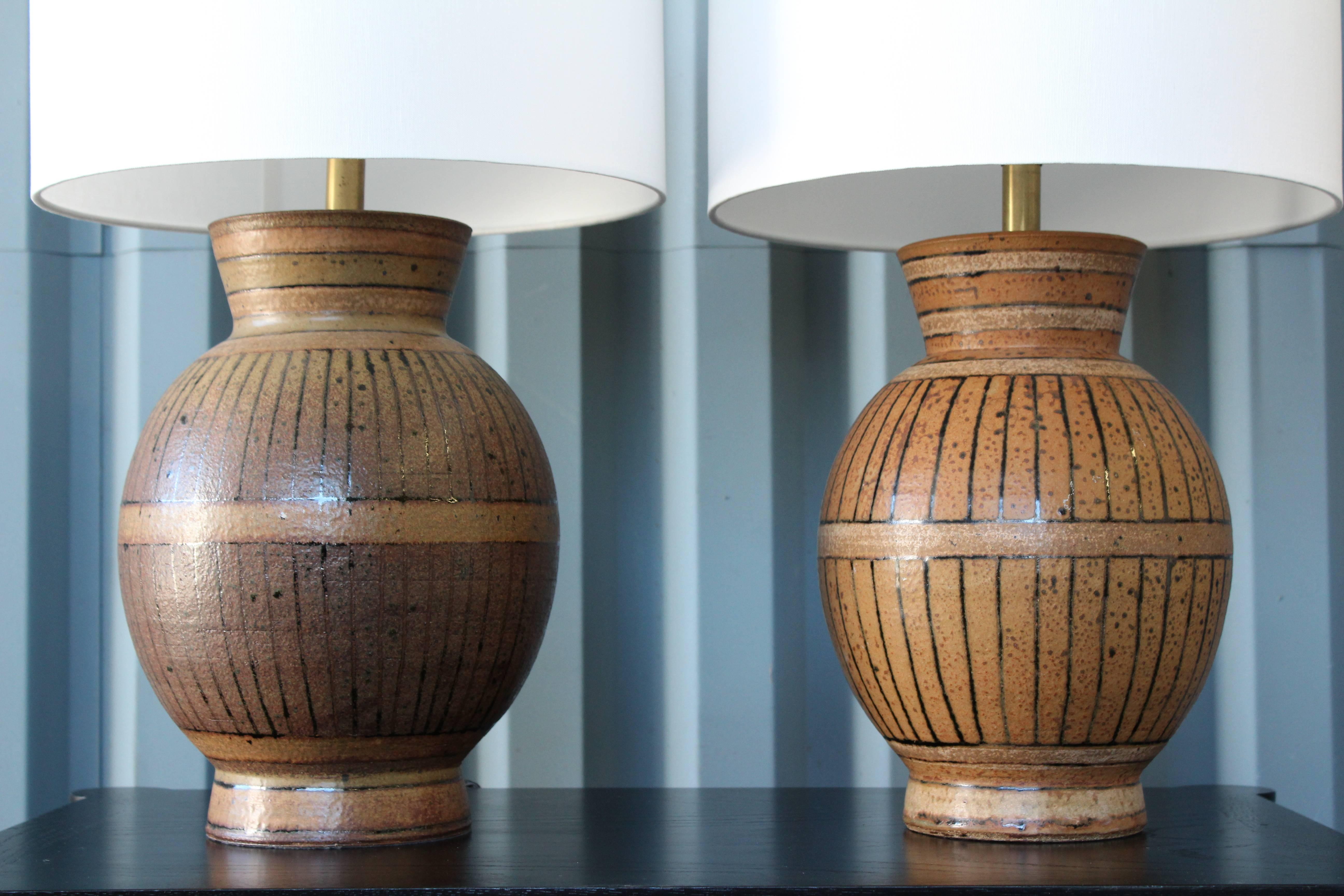 Pair of 1960s stoneware lamps by Brent Bennett. The pair have been recently rewired in brown twisted silk cording and include new white linen shades topped off with a brass finial. Each lamp is signed near the base. One remaining label on the bottom
