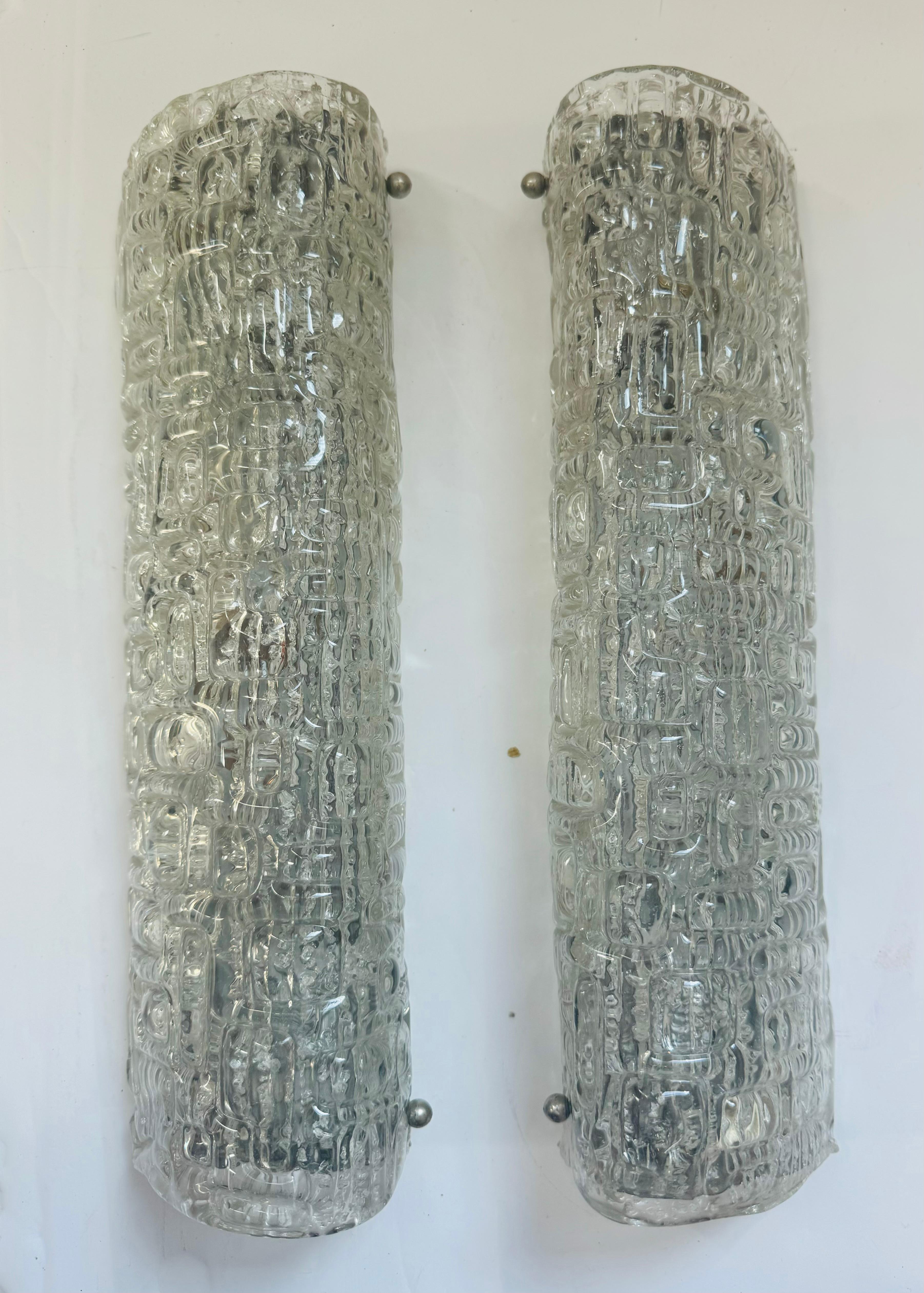 Ein schwedisches Paar aus den 1960er Jahren  Wandlampen aus strukturiertem Kristallglas mit verchromten Abdeckungen und Beschlägen. Je zwei Lichtquellen. Kandelaber-Fassungen.