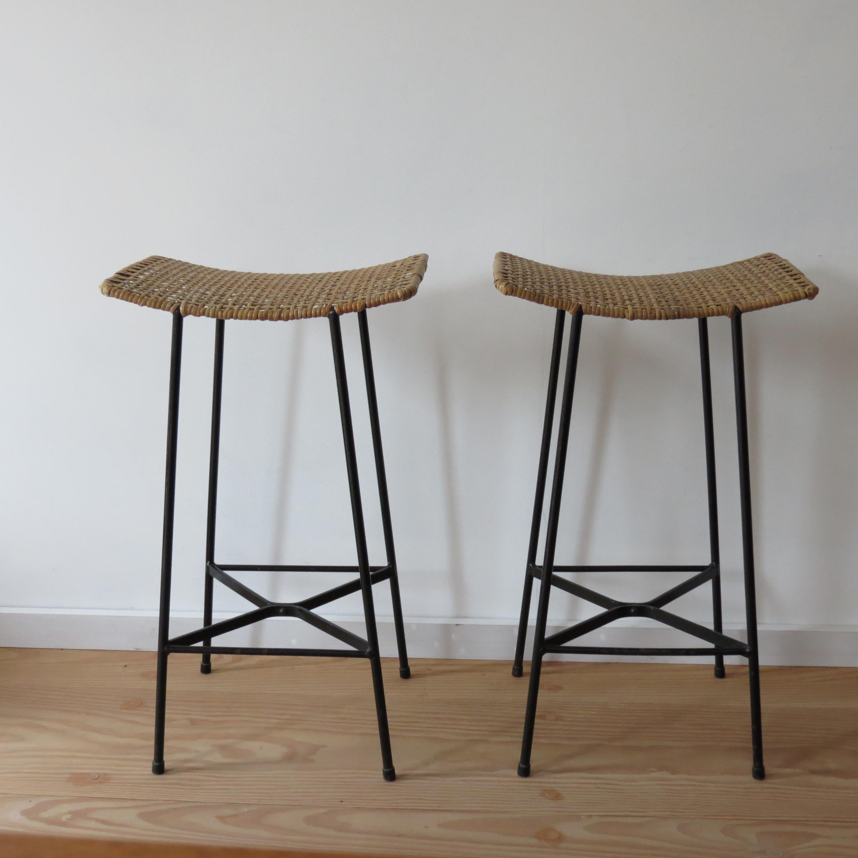 Pair of good quality metal and cane stools. Made from metal with stove enameled paint finish and cane seats. They date from the 1960s and are very good quality. 
Both have new seats and have been newly re-caned. Some loss in areas to the enameled