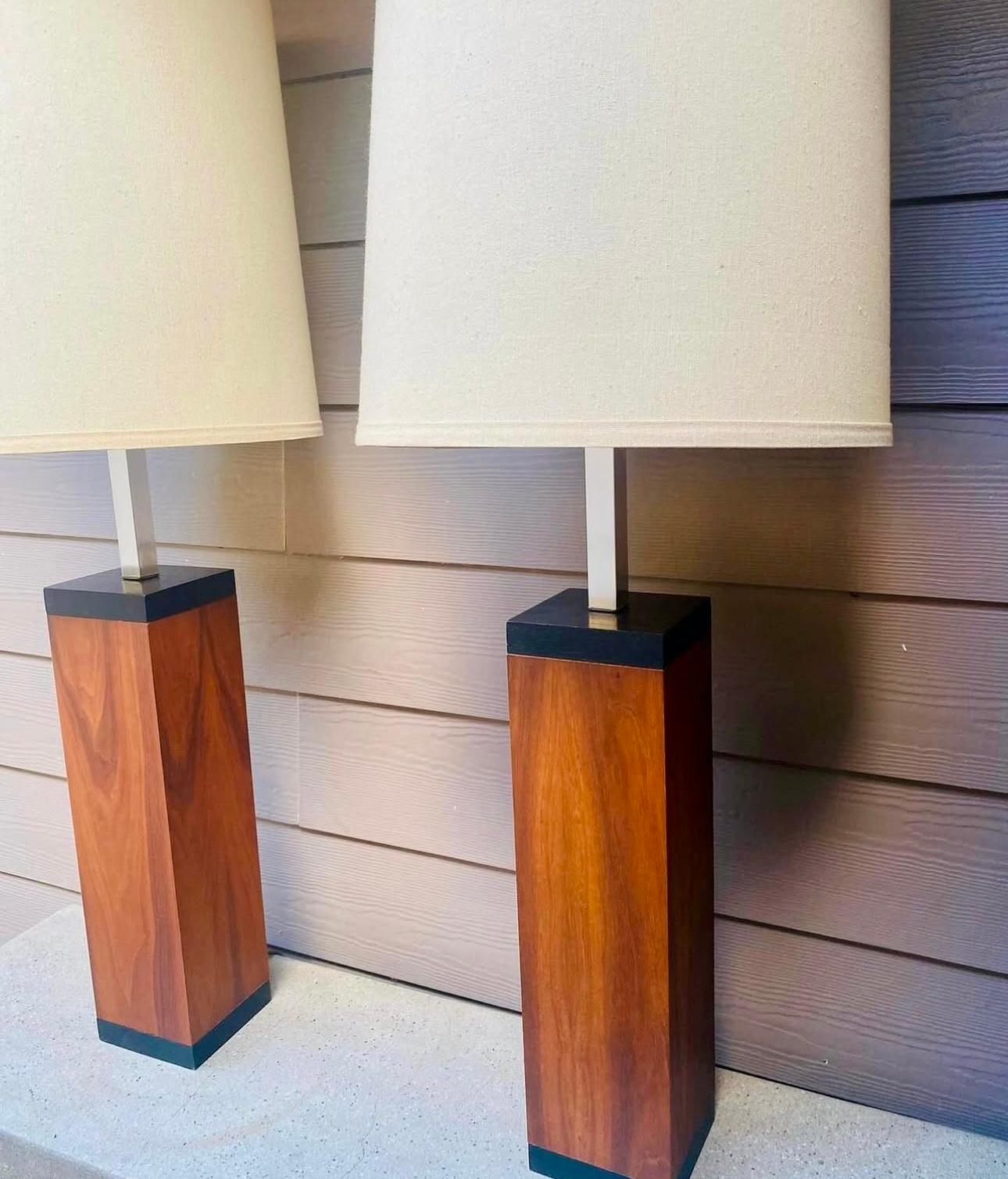 Queste lampade della metà del secolo scorso presentano un design elegante e minimalista, caratteristico dell'estetica dell'epoca. Ogni lampada ha una base rettangolare in legno di noce con una ricca e calda venatura del legno, completata da accenti